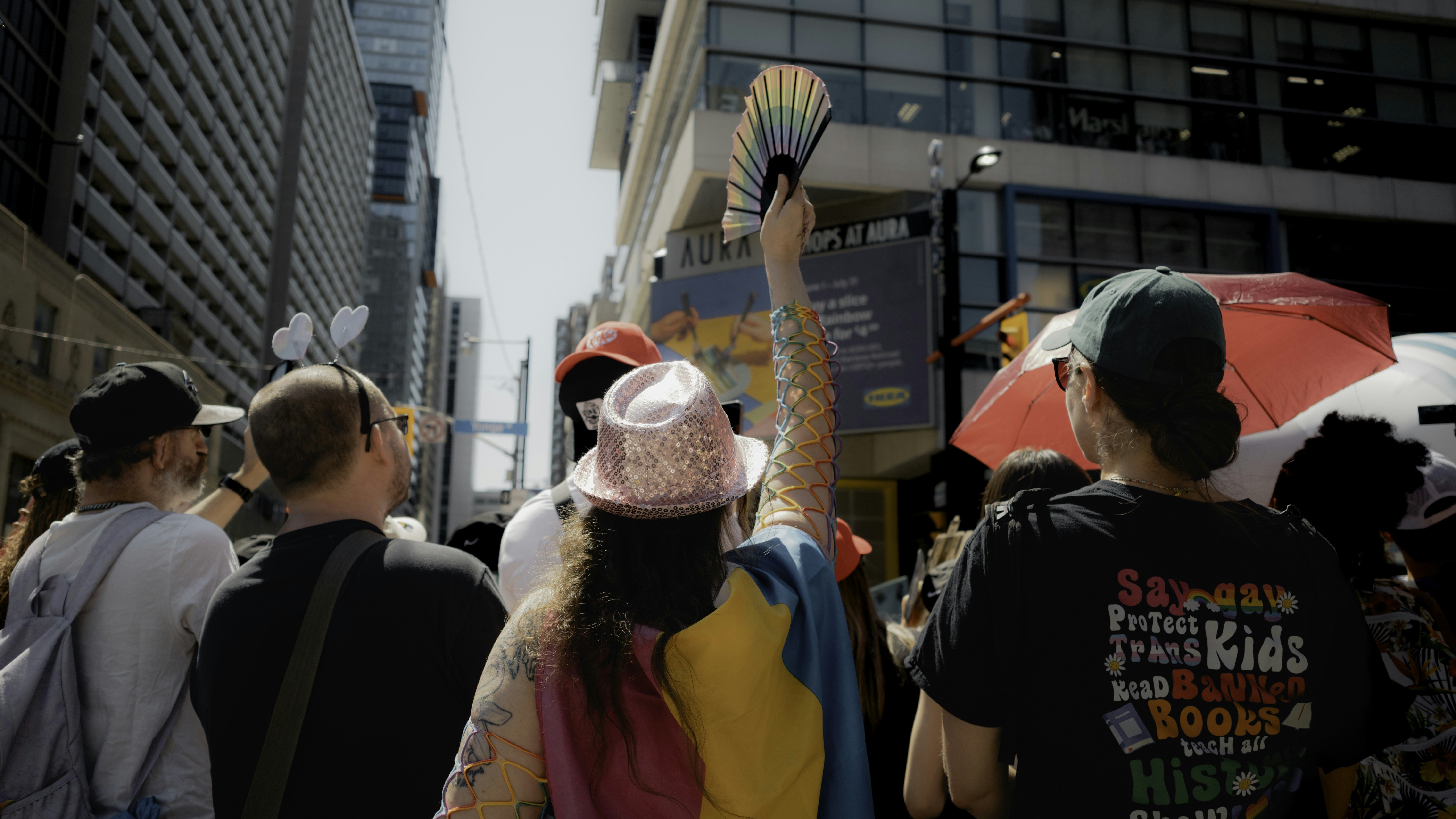 People celebrate at a pride parade, holding a fan.