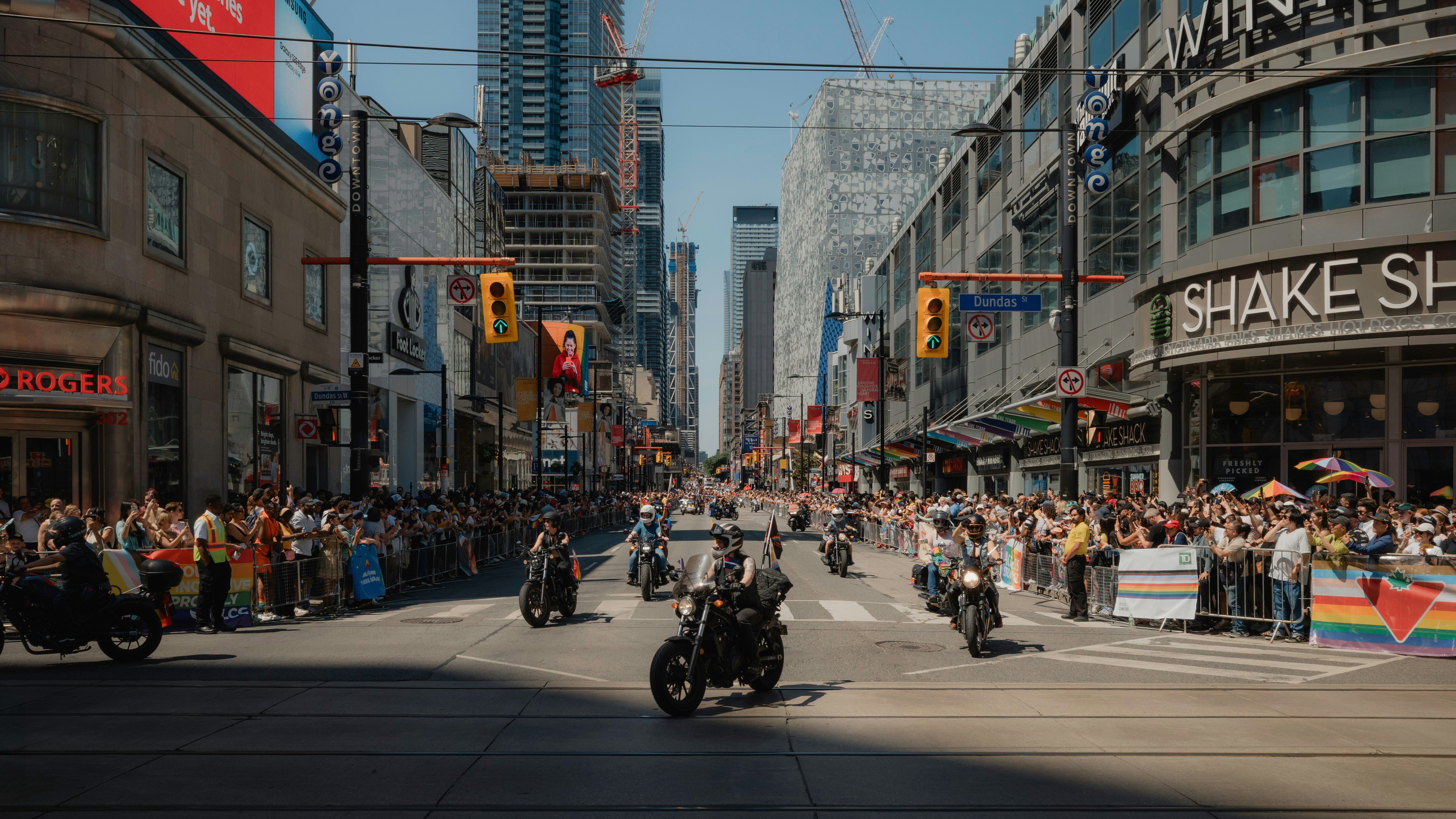 Motorcycles ride through a busy city street parade.