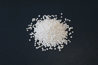 A pile of white beads on a dark background.