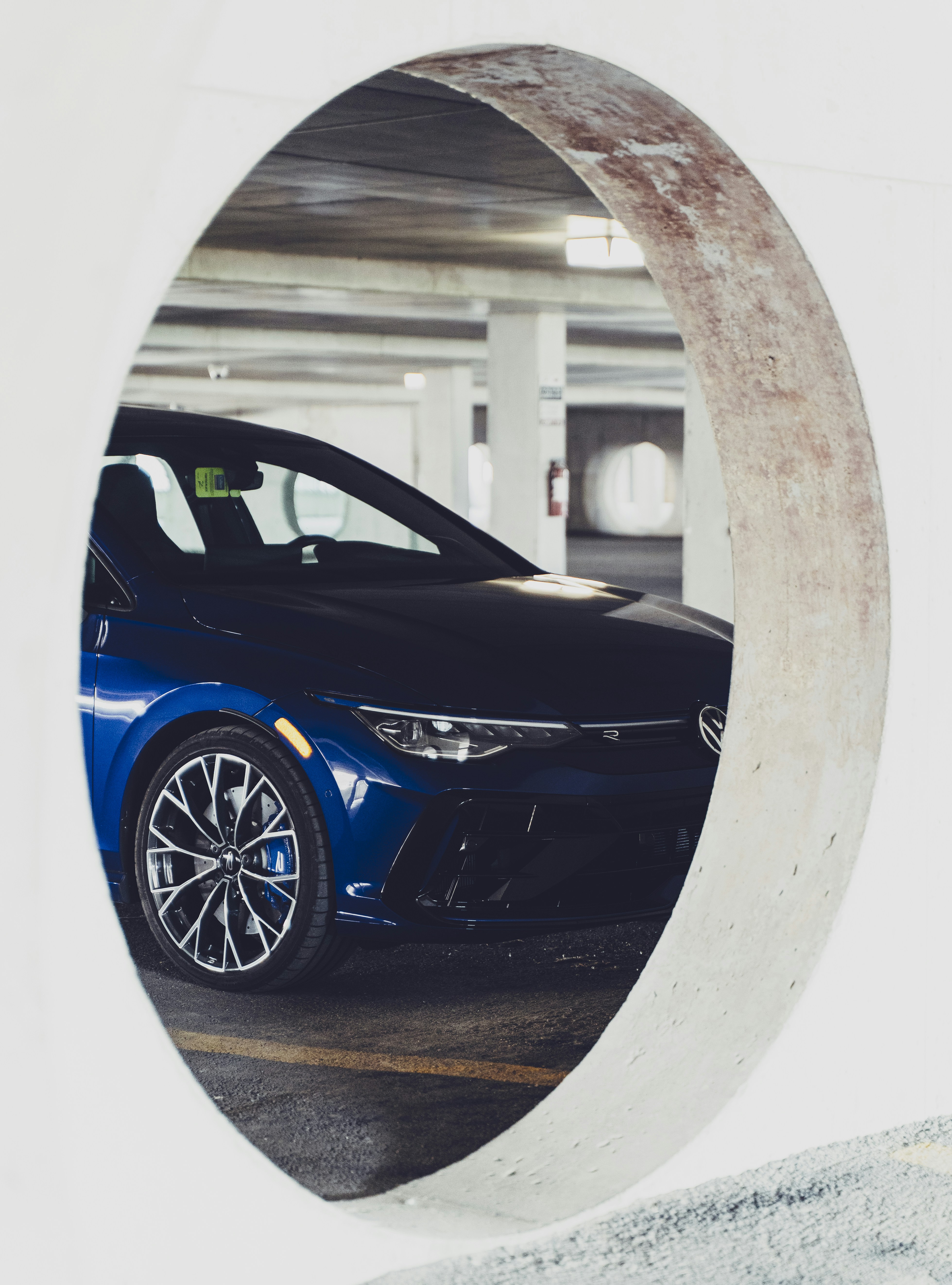 A blue car is viewed through an oval opening