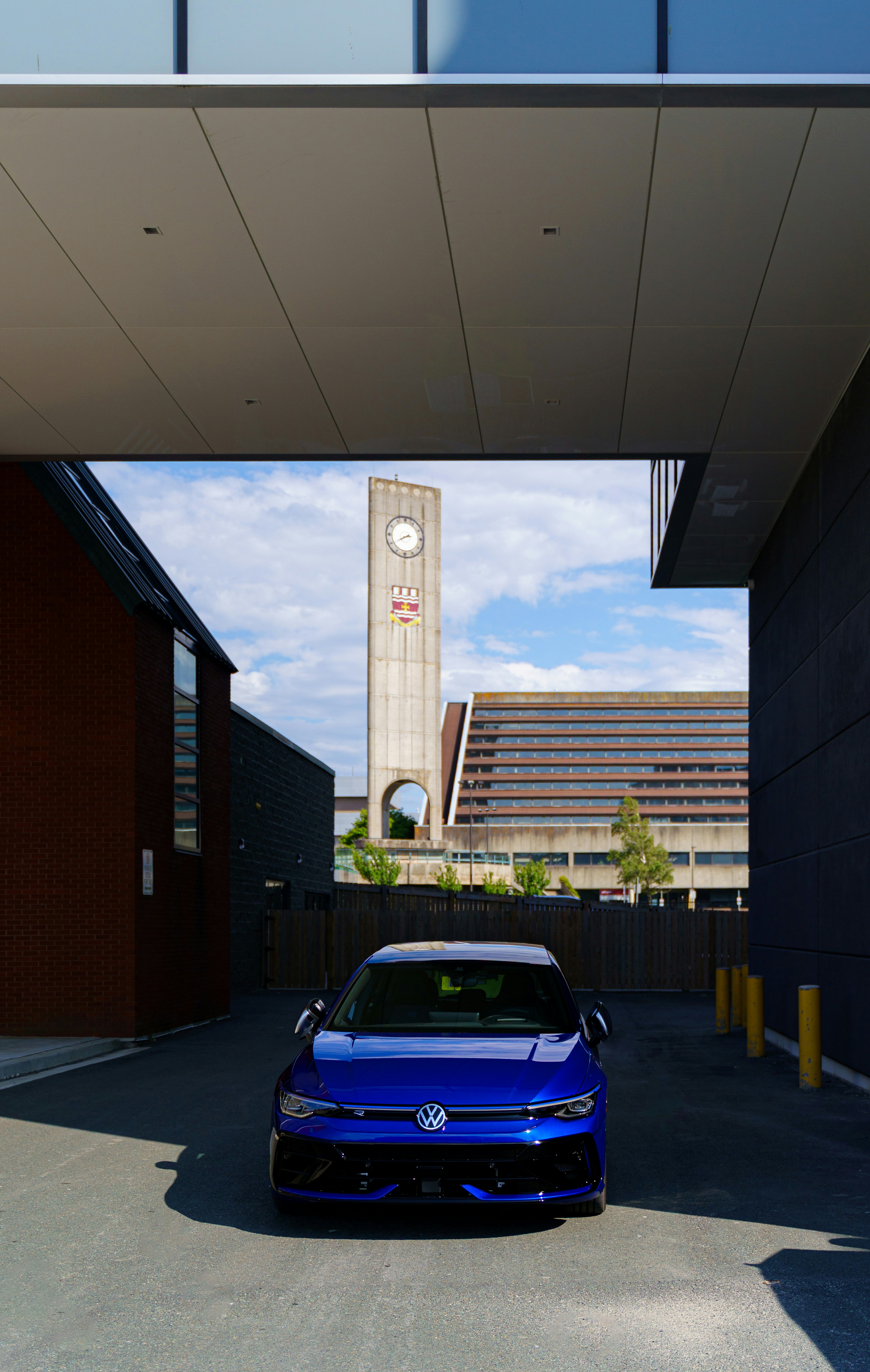 A blue car is parked under a building