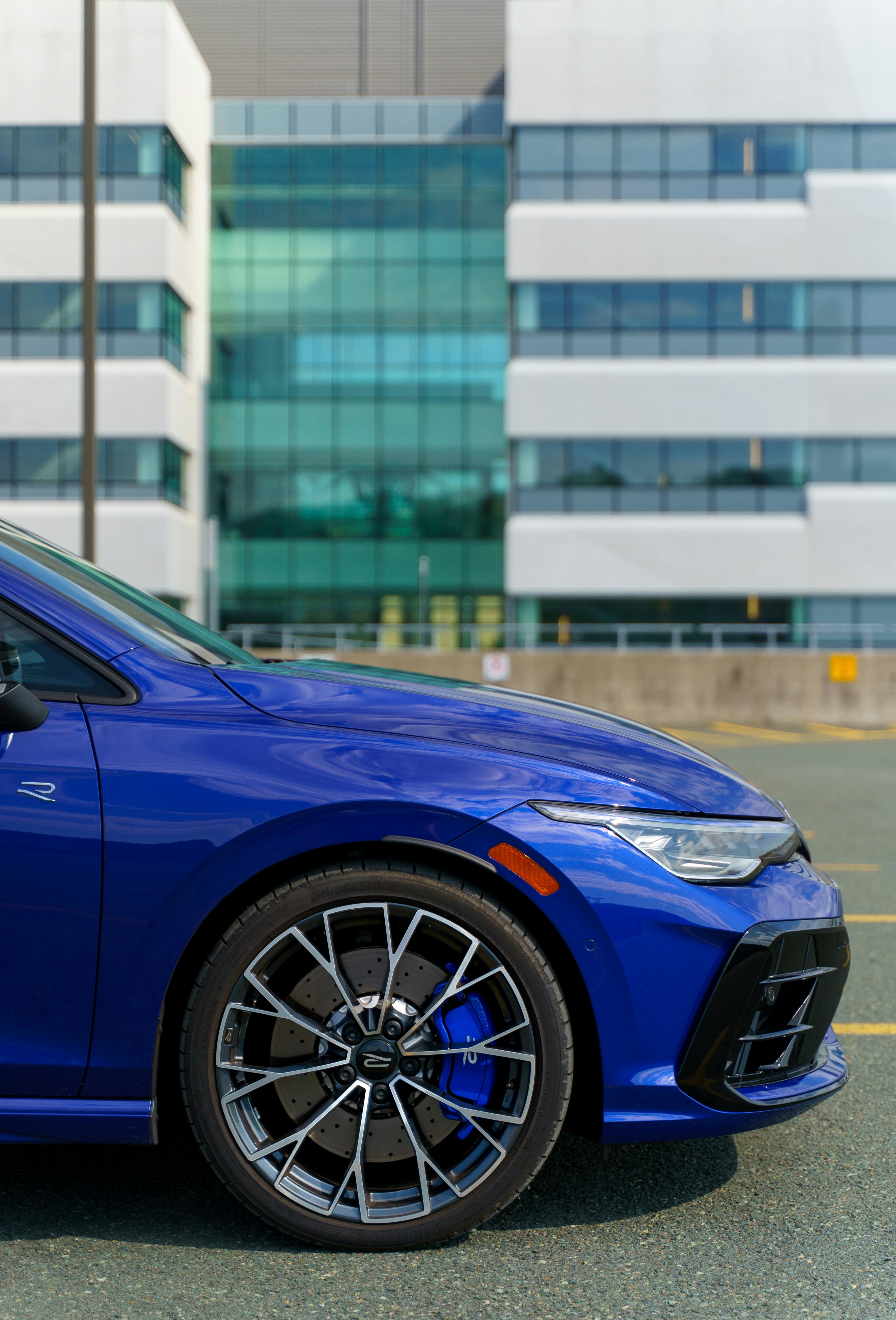 A blue car sits in front of a modern building