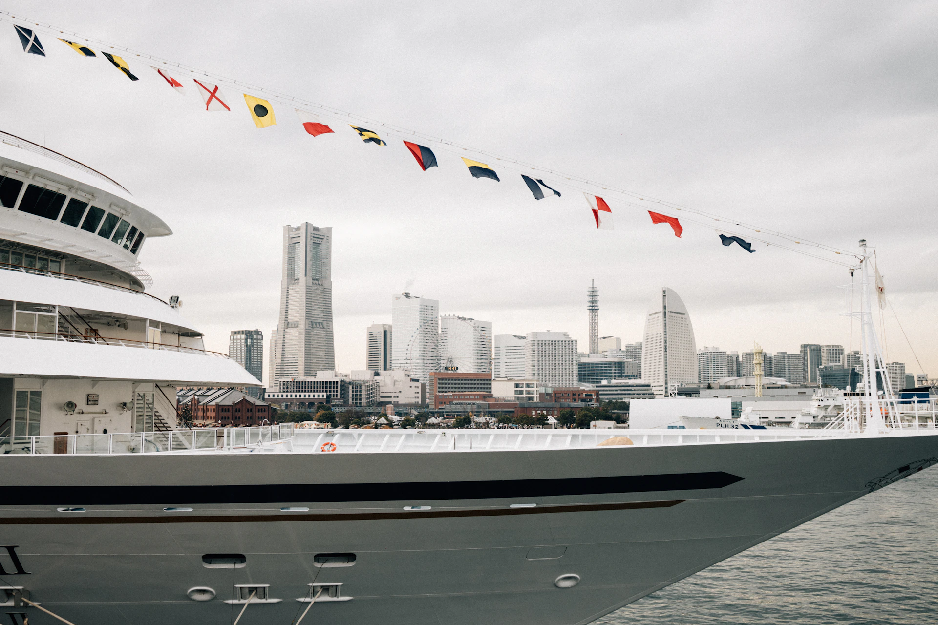 A large yacht sails with city skyline in the background