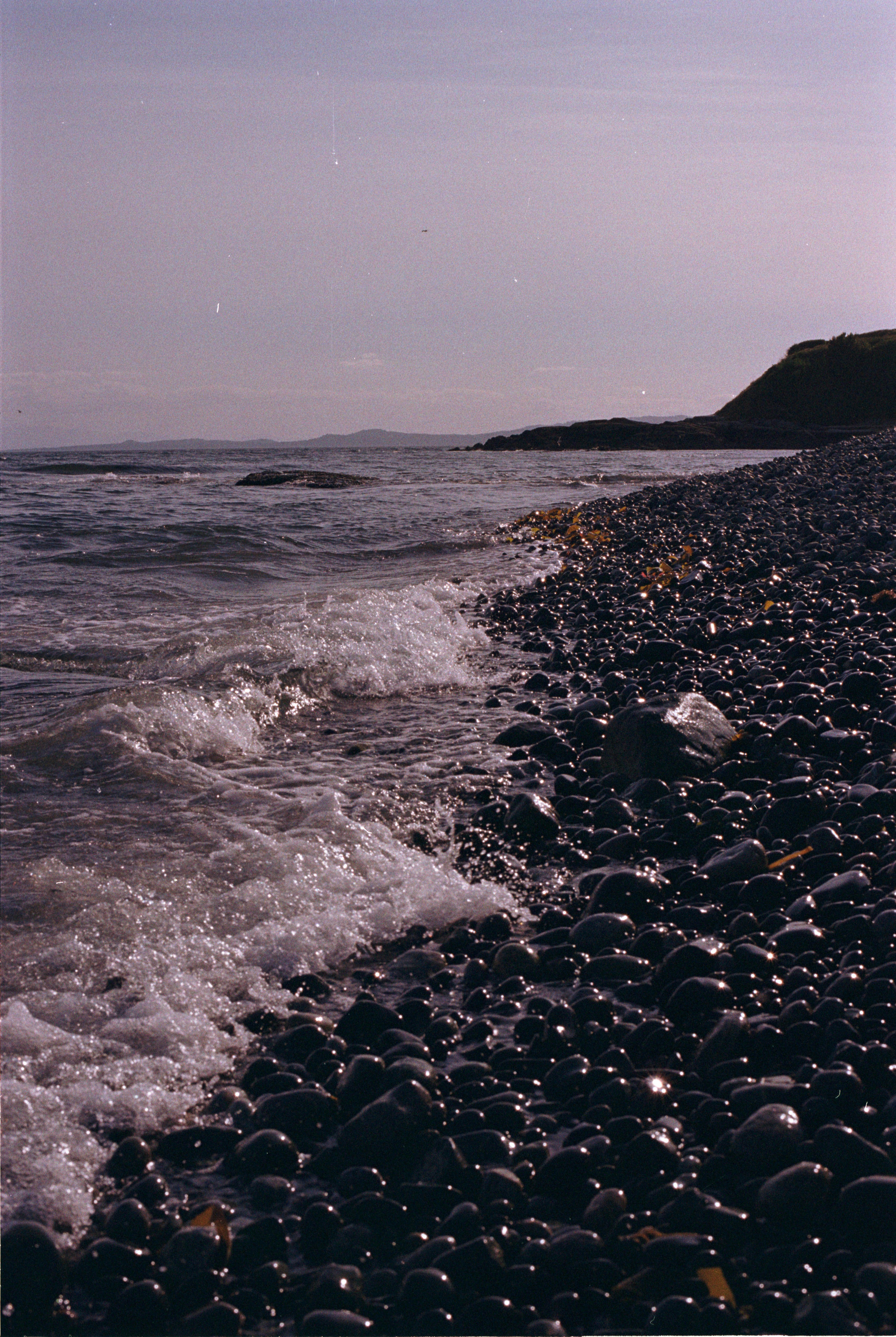 As ondas quebram em uma praia rochosa.
