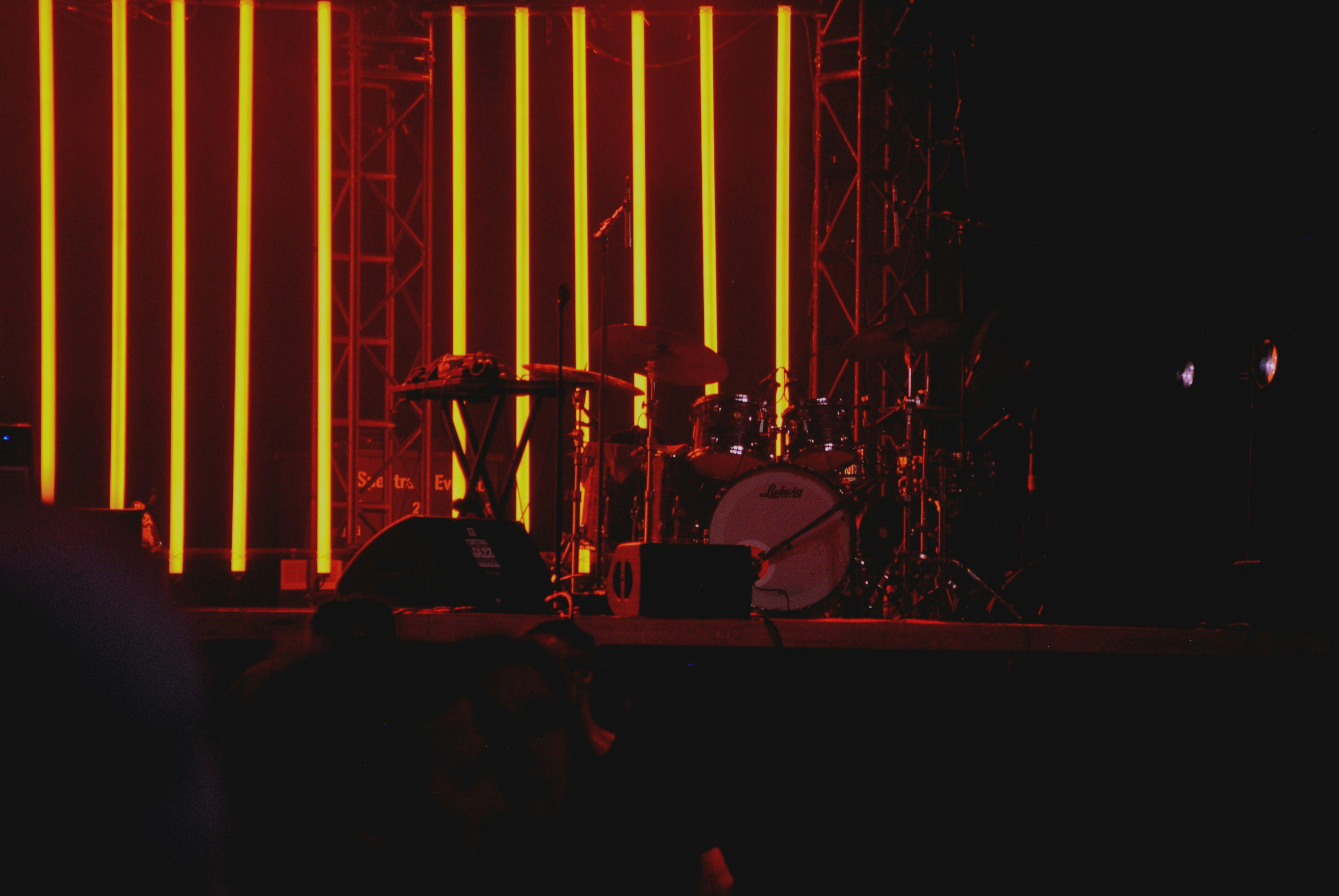A drum set and stage lights in a dark setting.