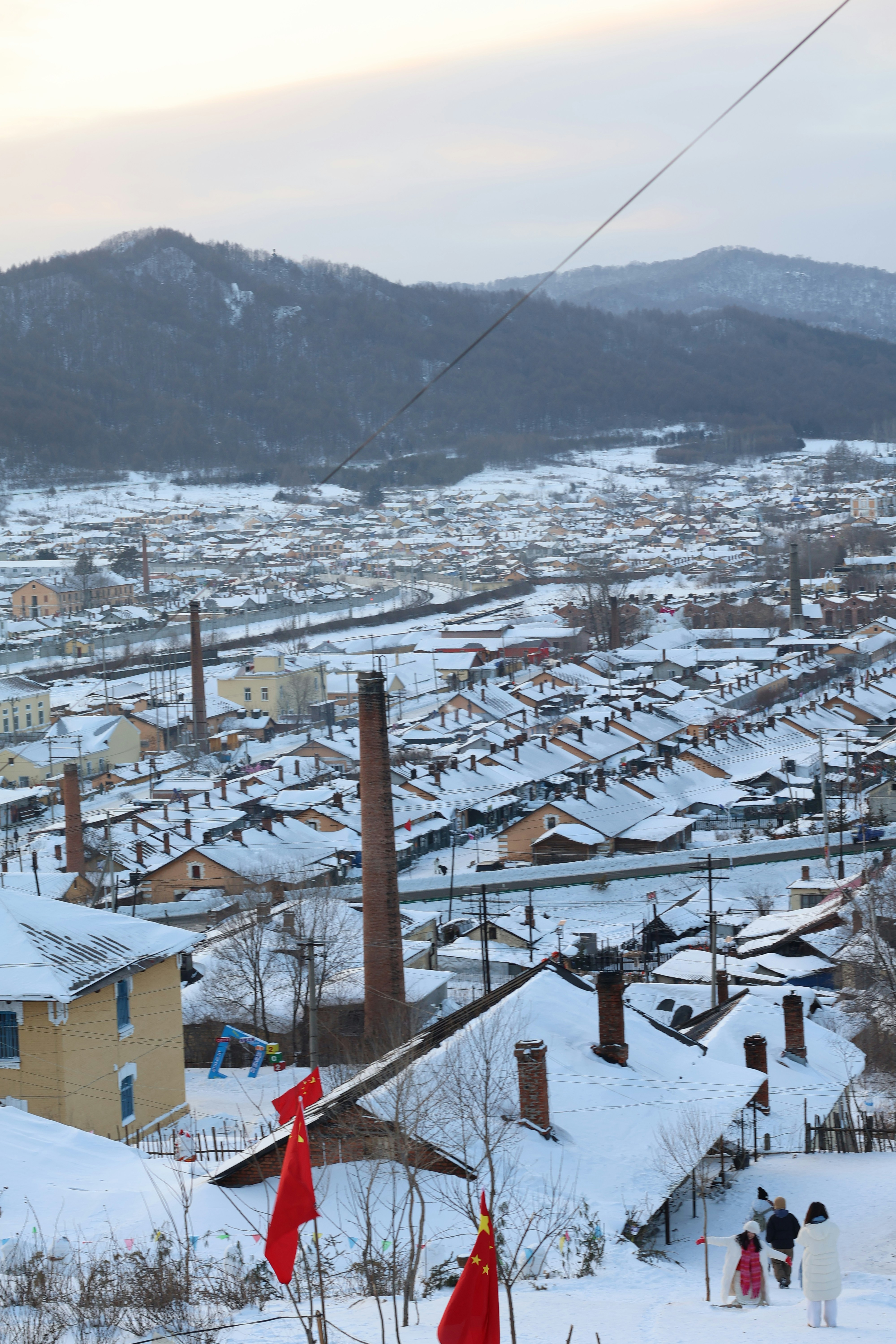 Snowy cityscape with chinese flags and mountains.