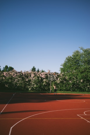 A person plays basketball on an outdoor court.