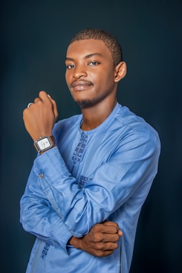 A man poses in a blue embroidered shirt.