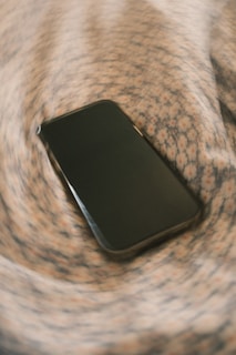 A smartphone rests on a swirling pattern.