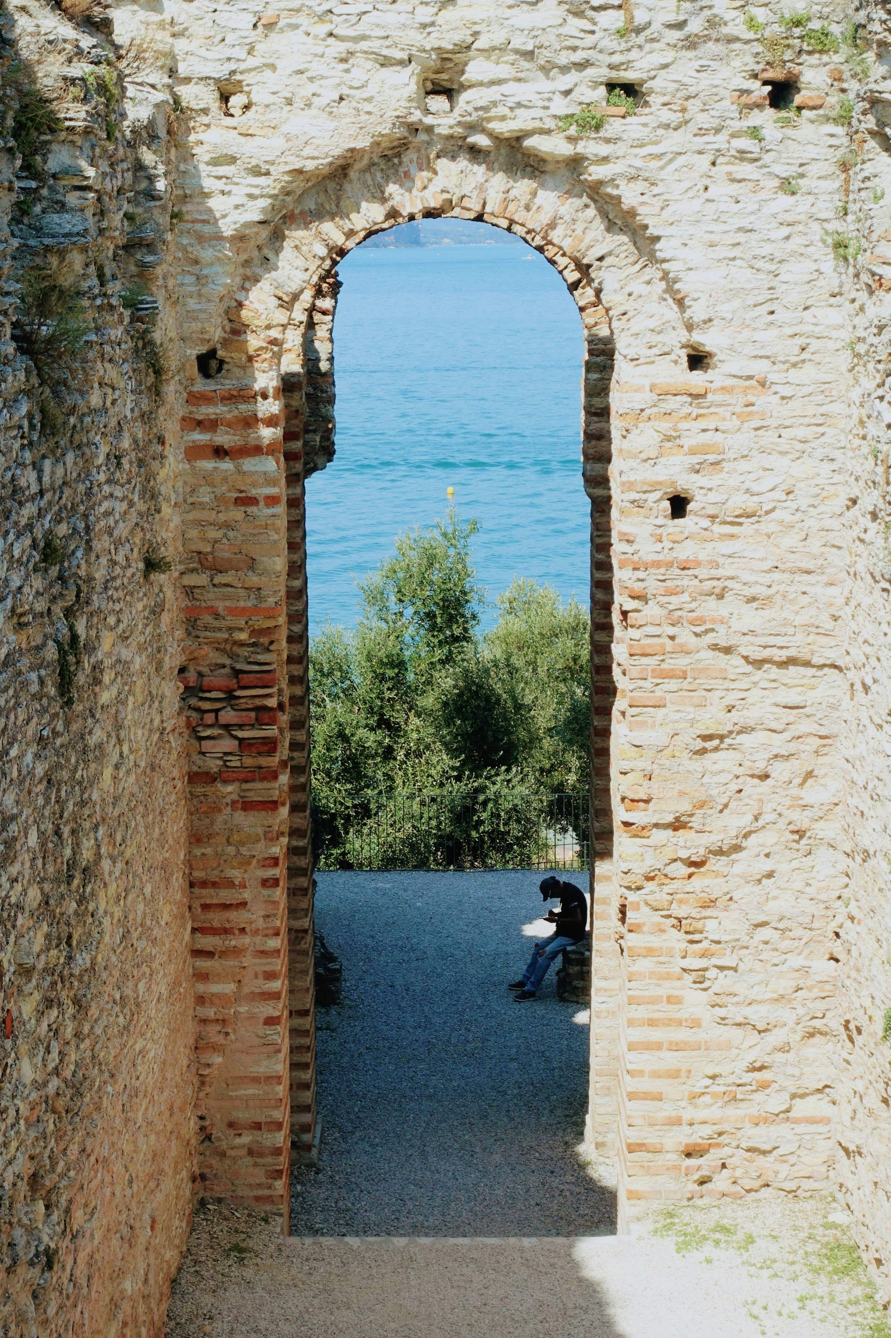Archway frames a view of water and a person.