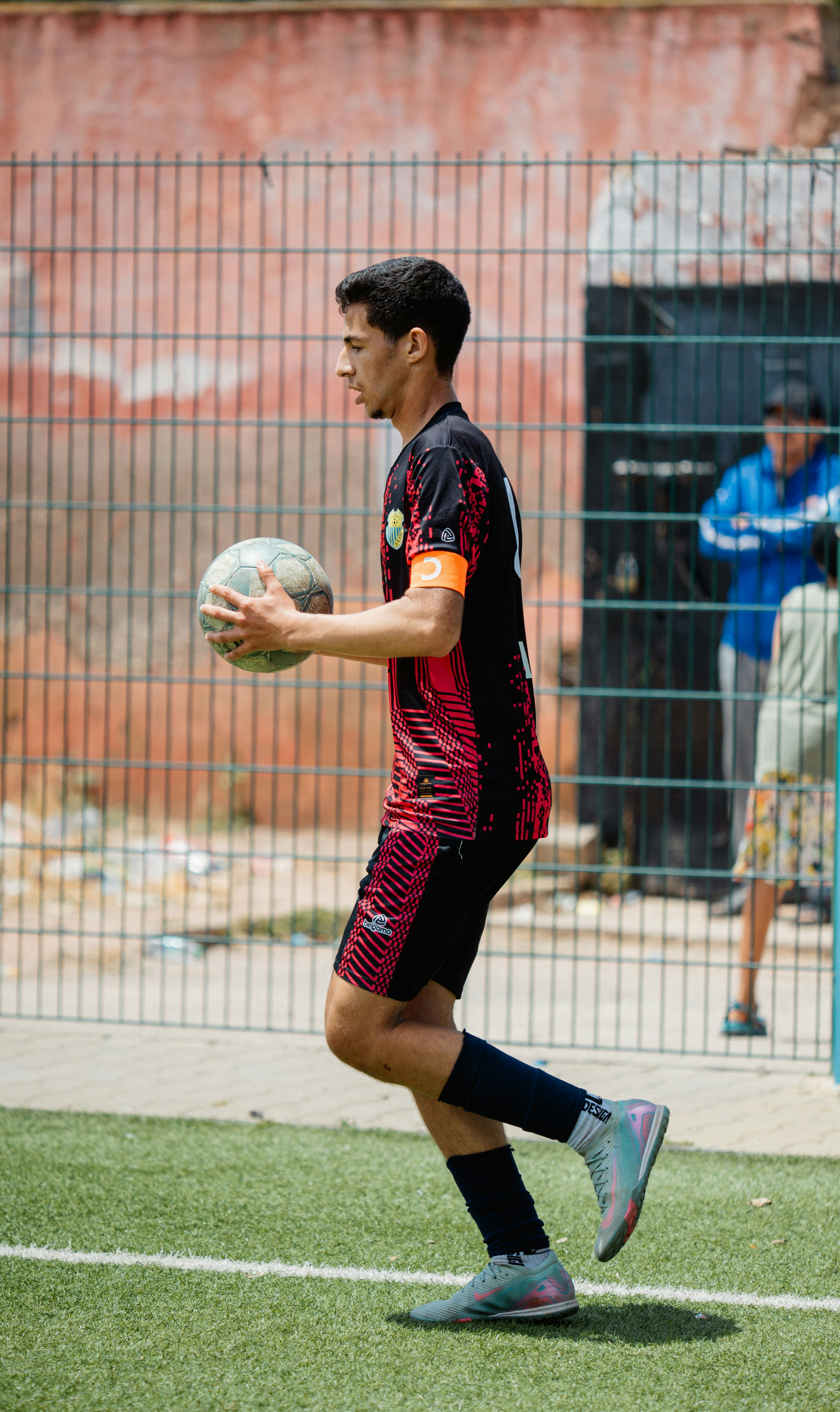 Seorang pemain sepak bola membawa bola di lapangan.