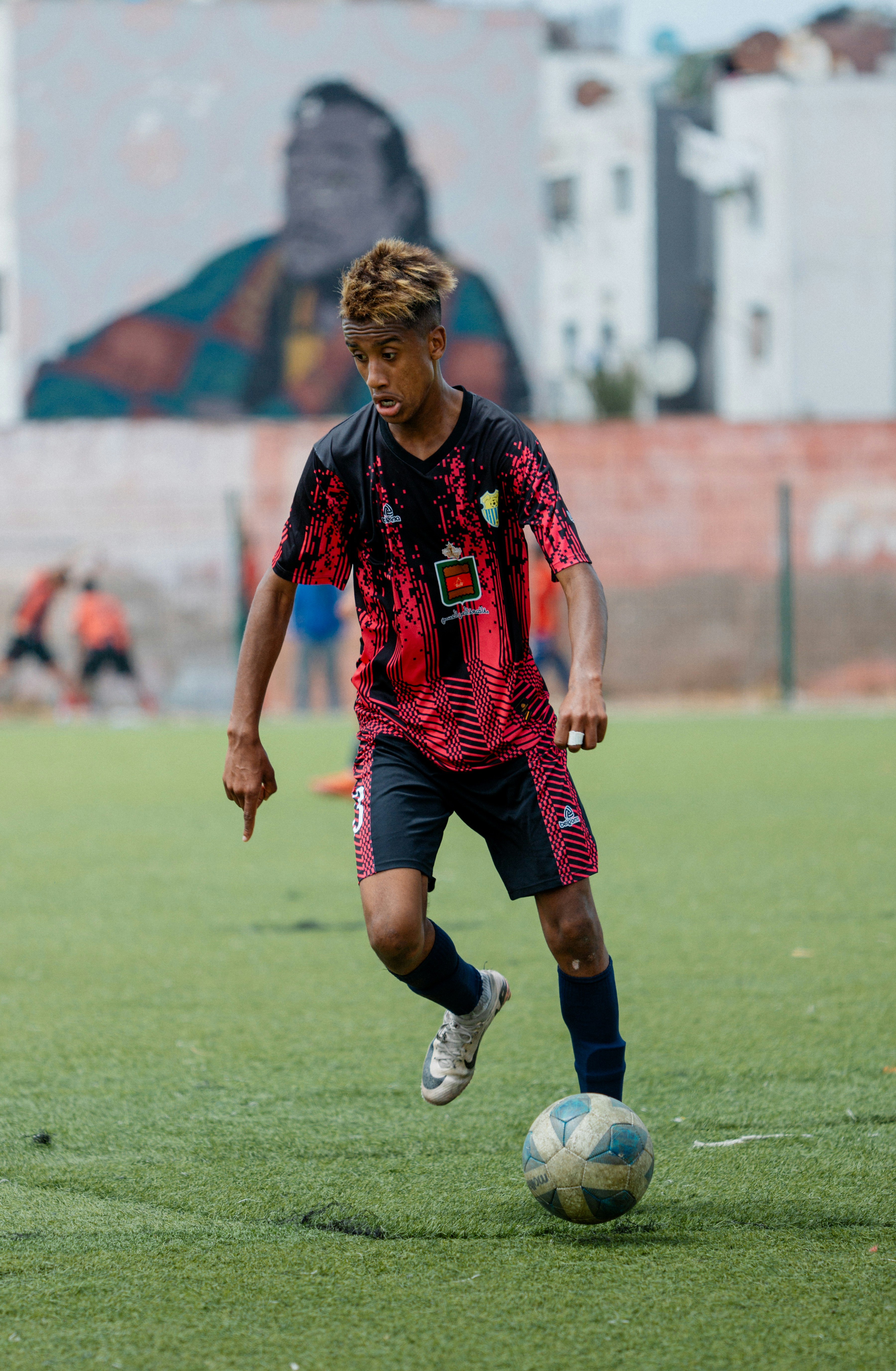 Pemain sepak bola menggiring bola di lapangan.