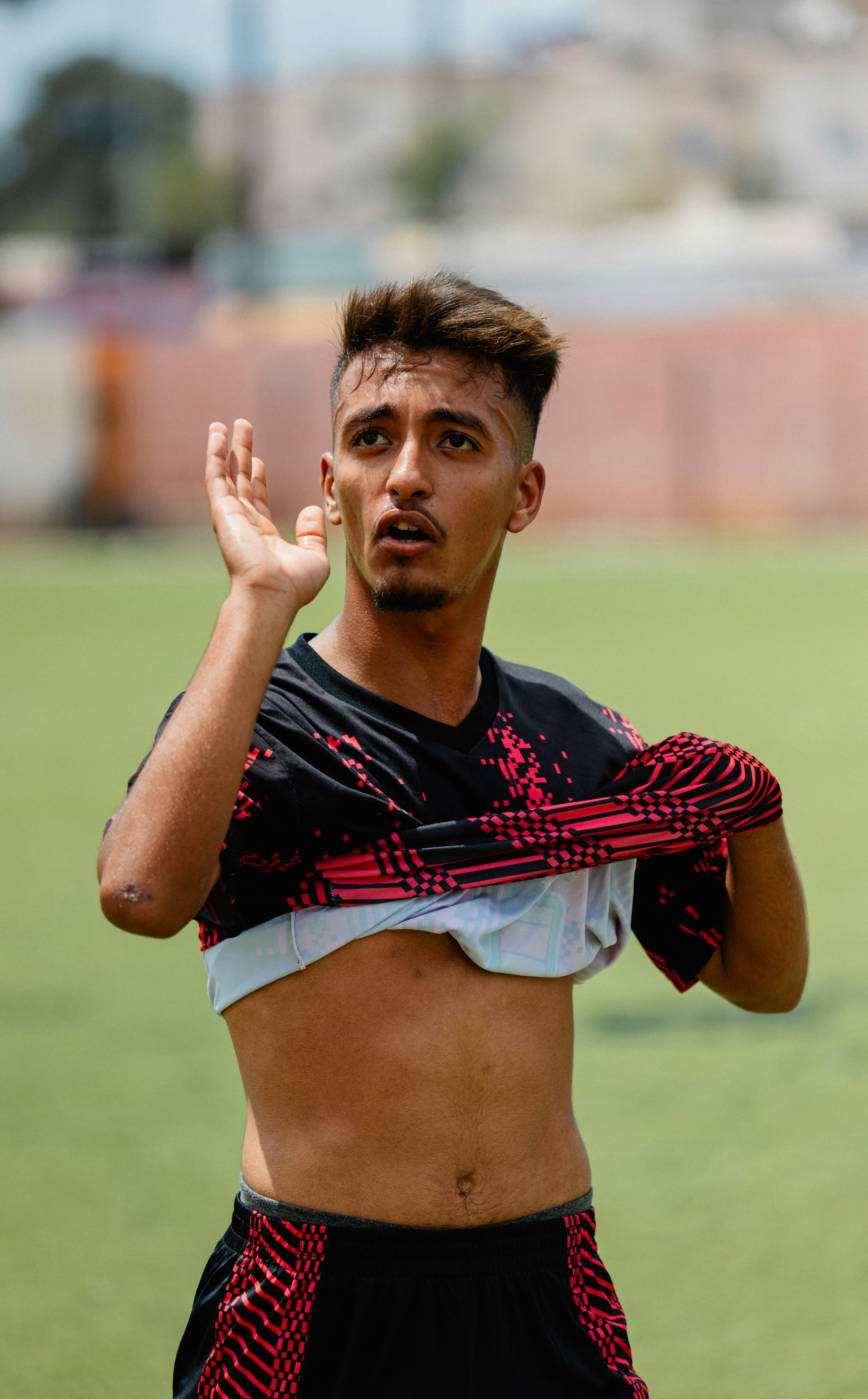 A soccer player is taking off his jersey.