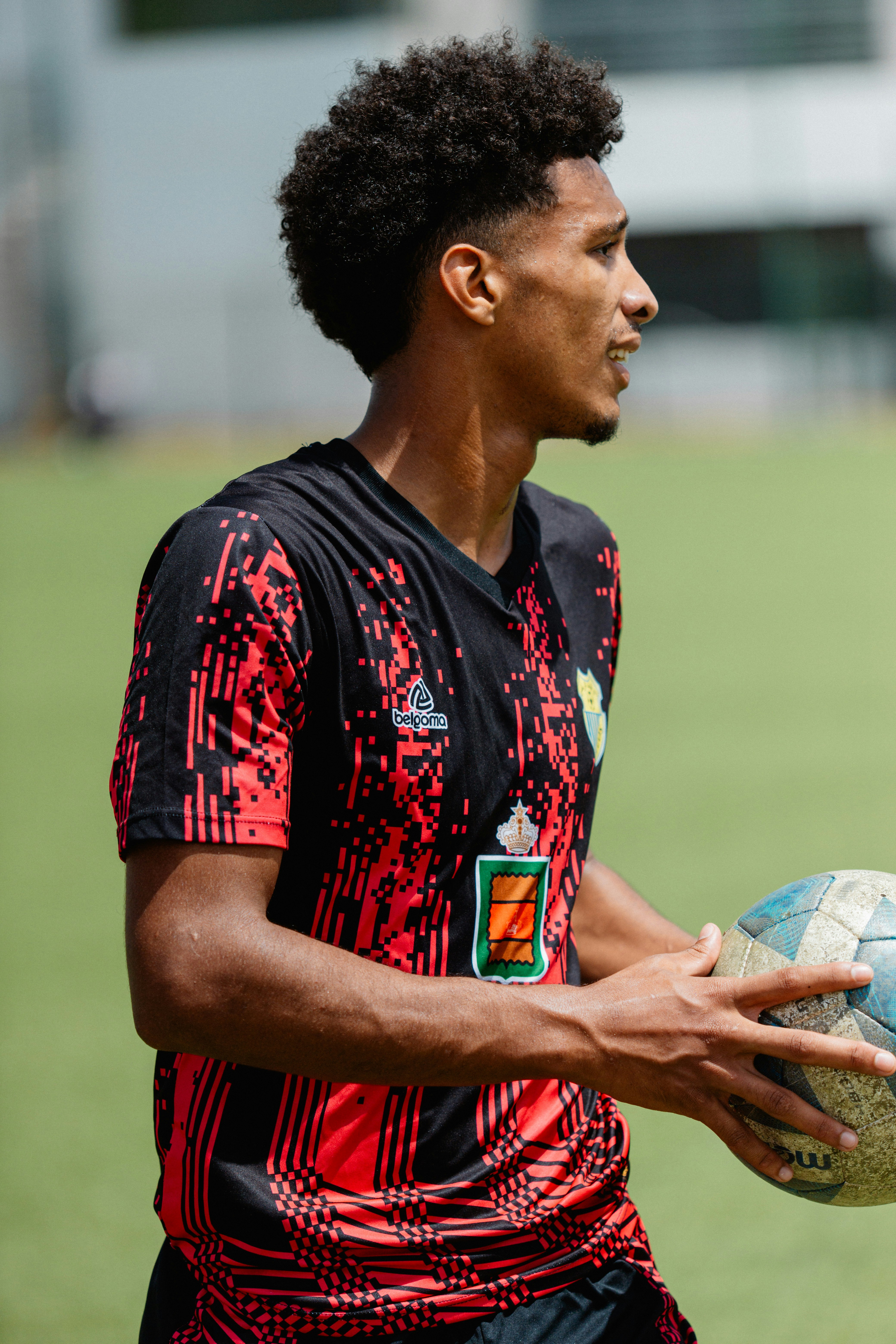 A soccer player holds a ball and looks aside.