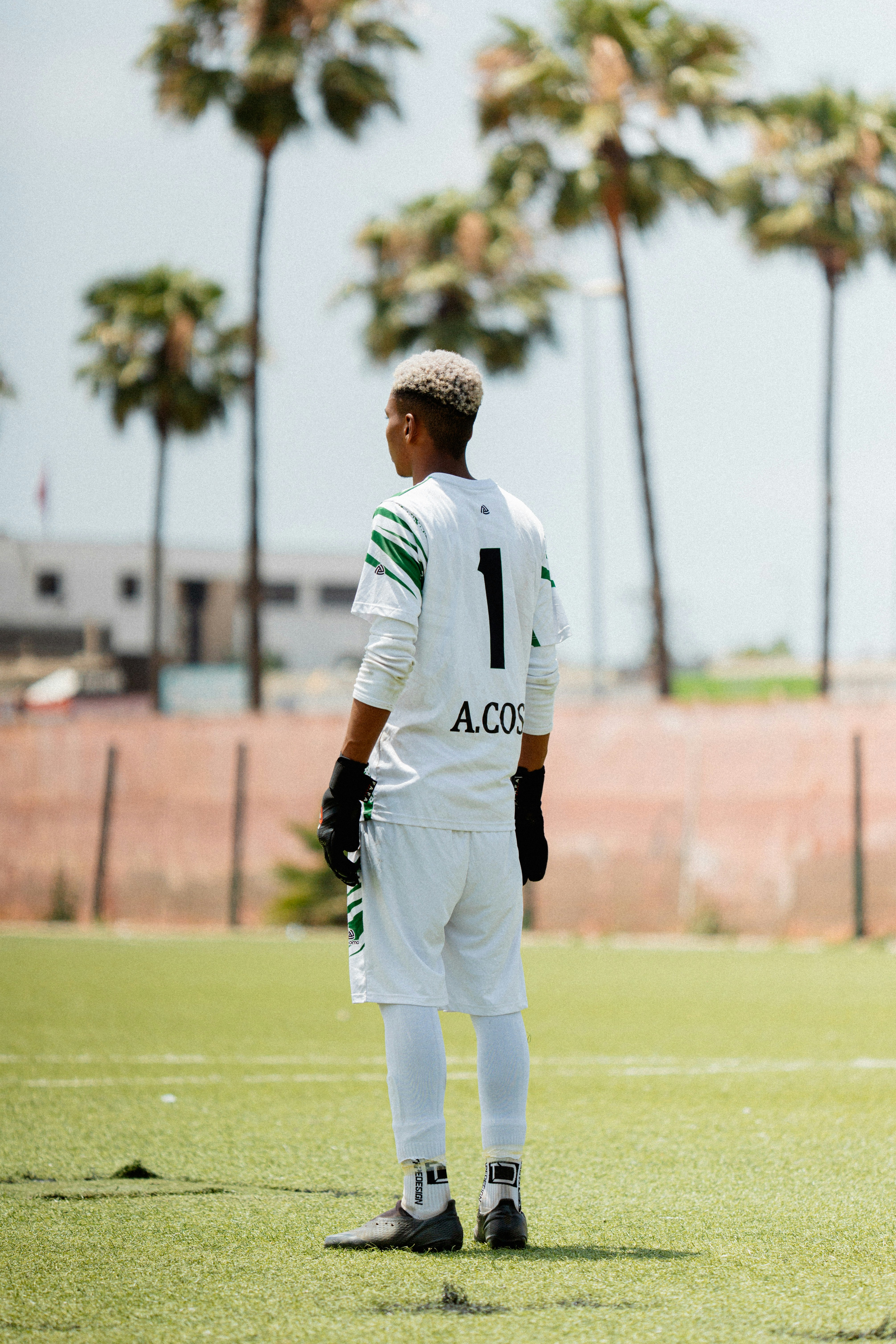 A soccer goalie stands on the field.