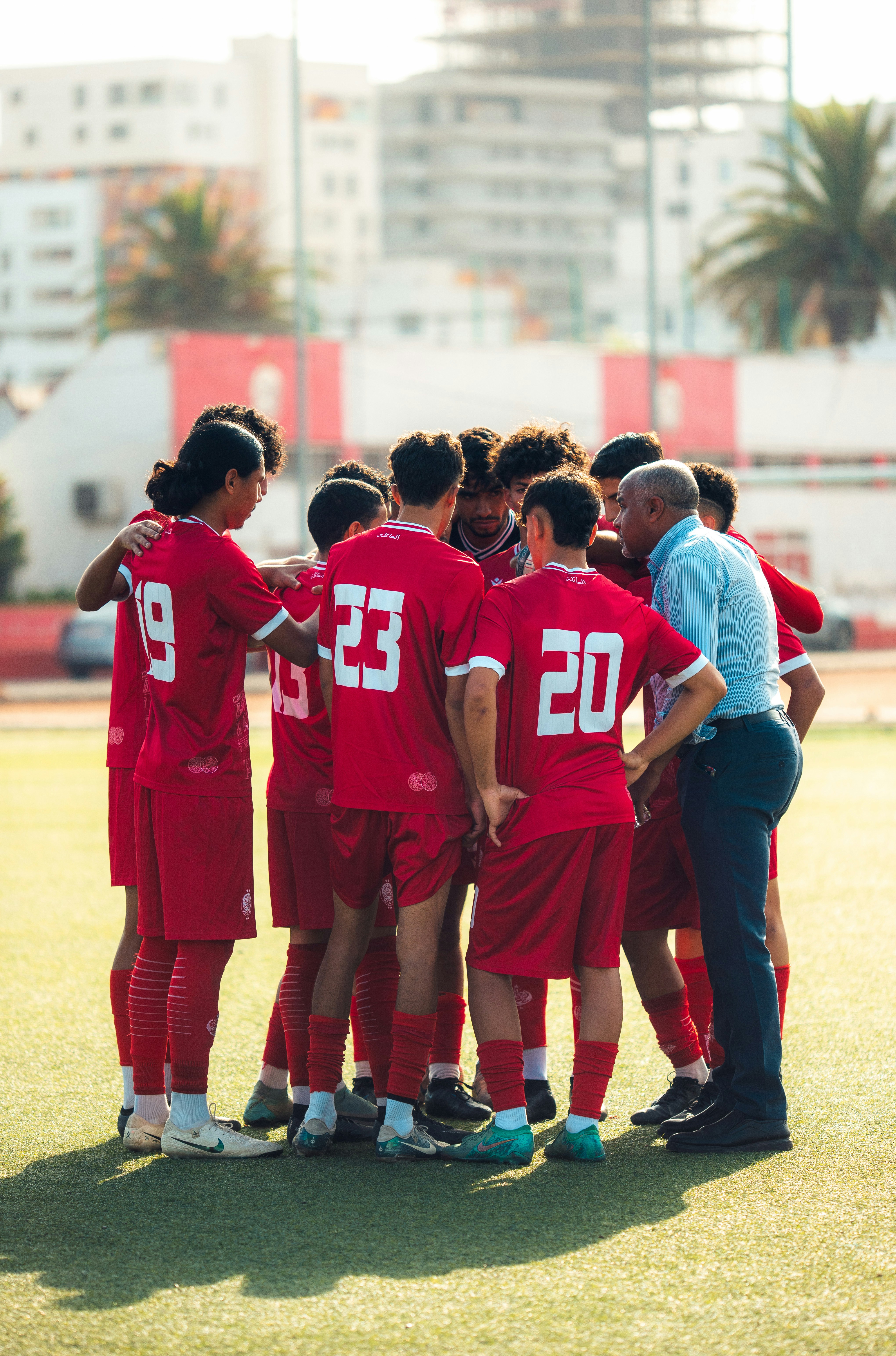 Soccer team huddles with coach on the field.