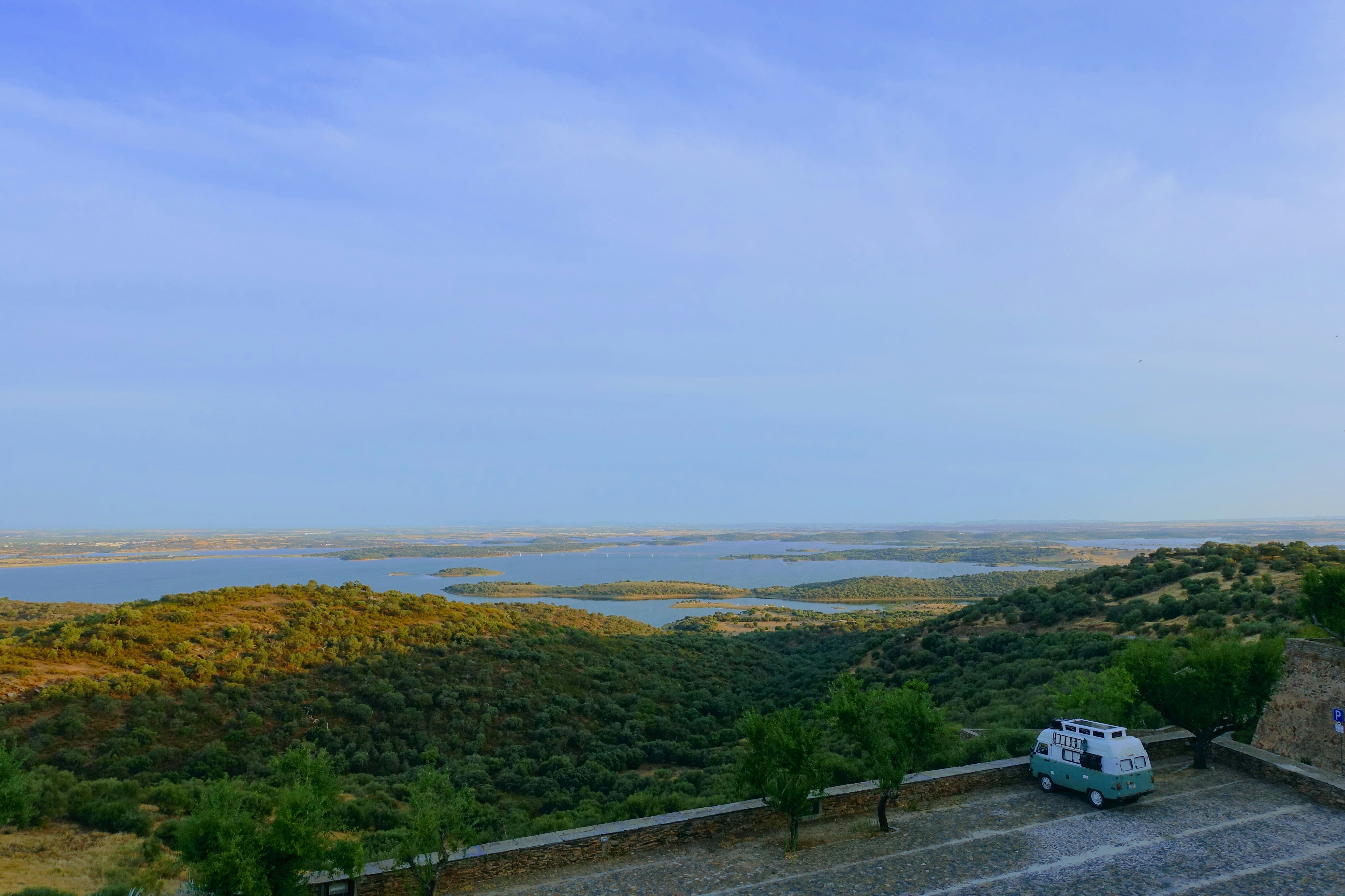 A camper van sits overlooking a scenic landscape.