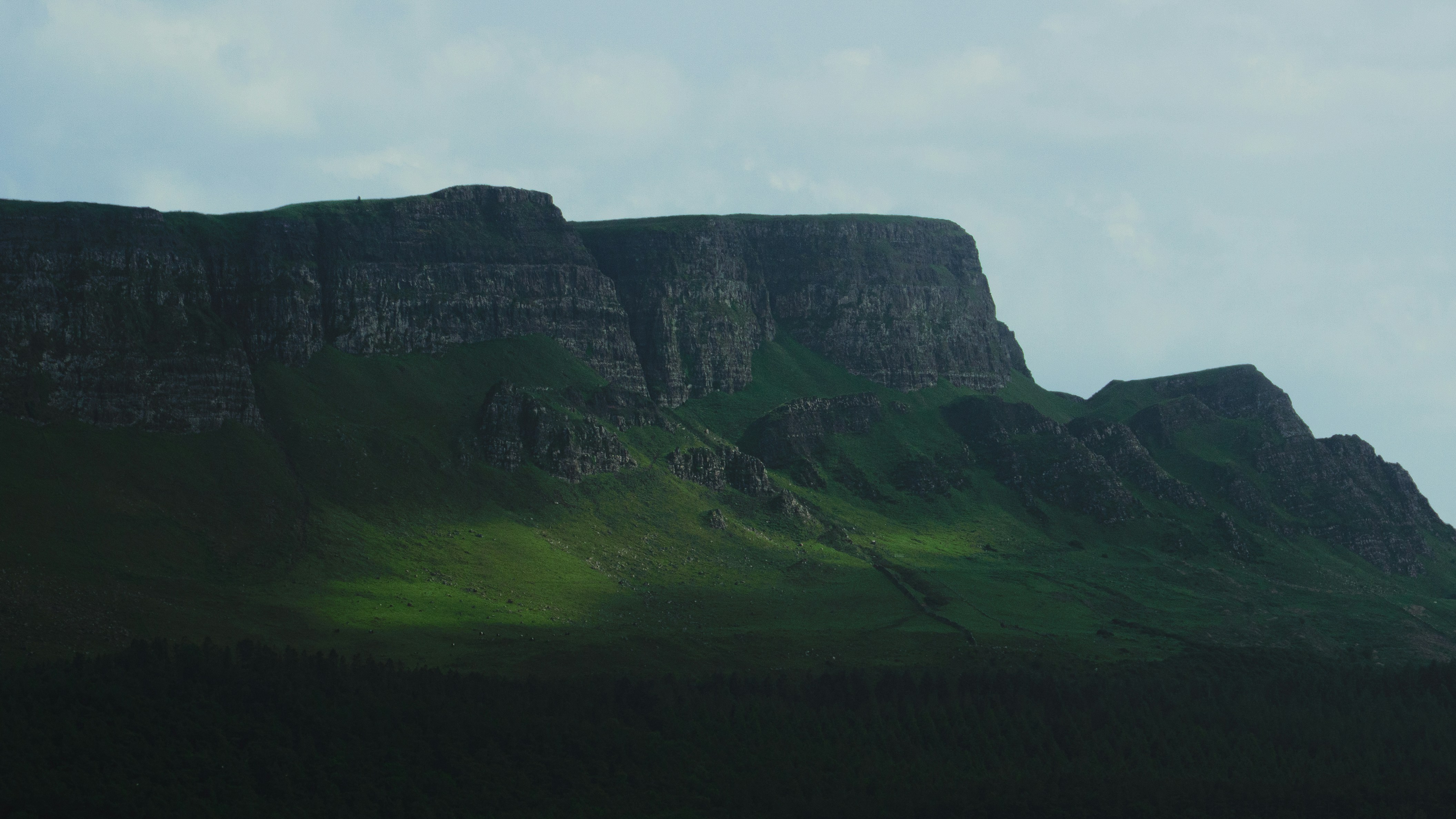 A lush green mountain against a cloudy sky.