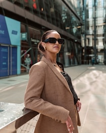 Stylish woman poses outdoors wearing sunglasses and a blazer.