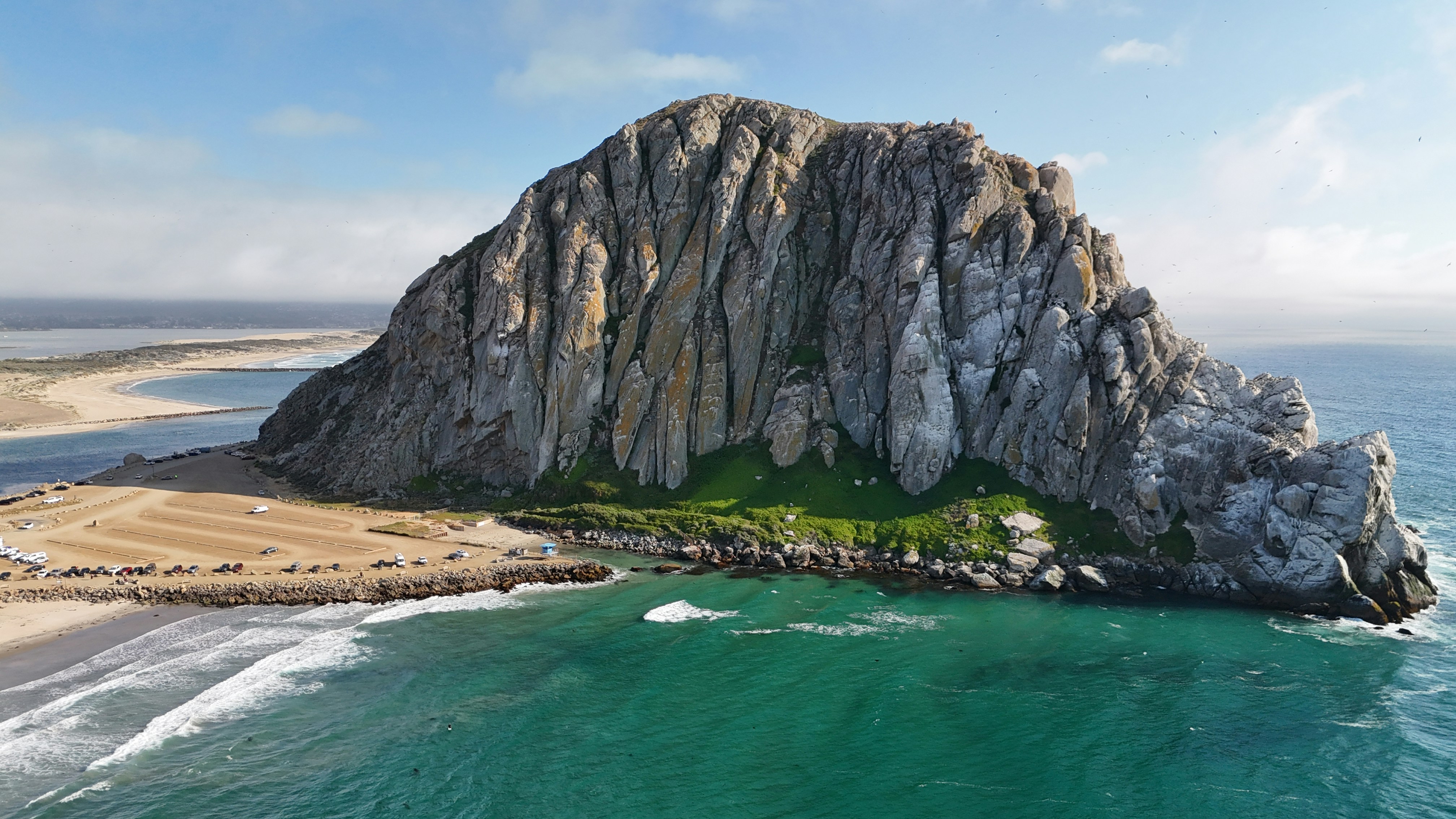 A towering volcanic rock formation rises dramatically from the Pacific