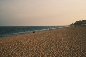 Sandy beach stretches along the ocean under a cloudy sky.