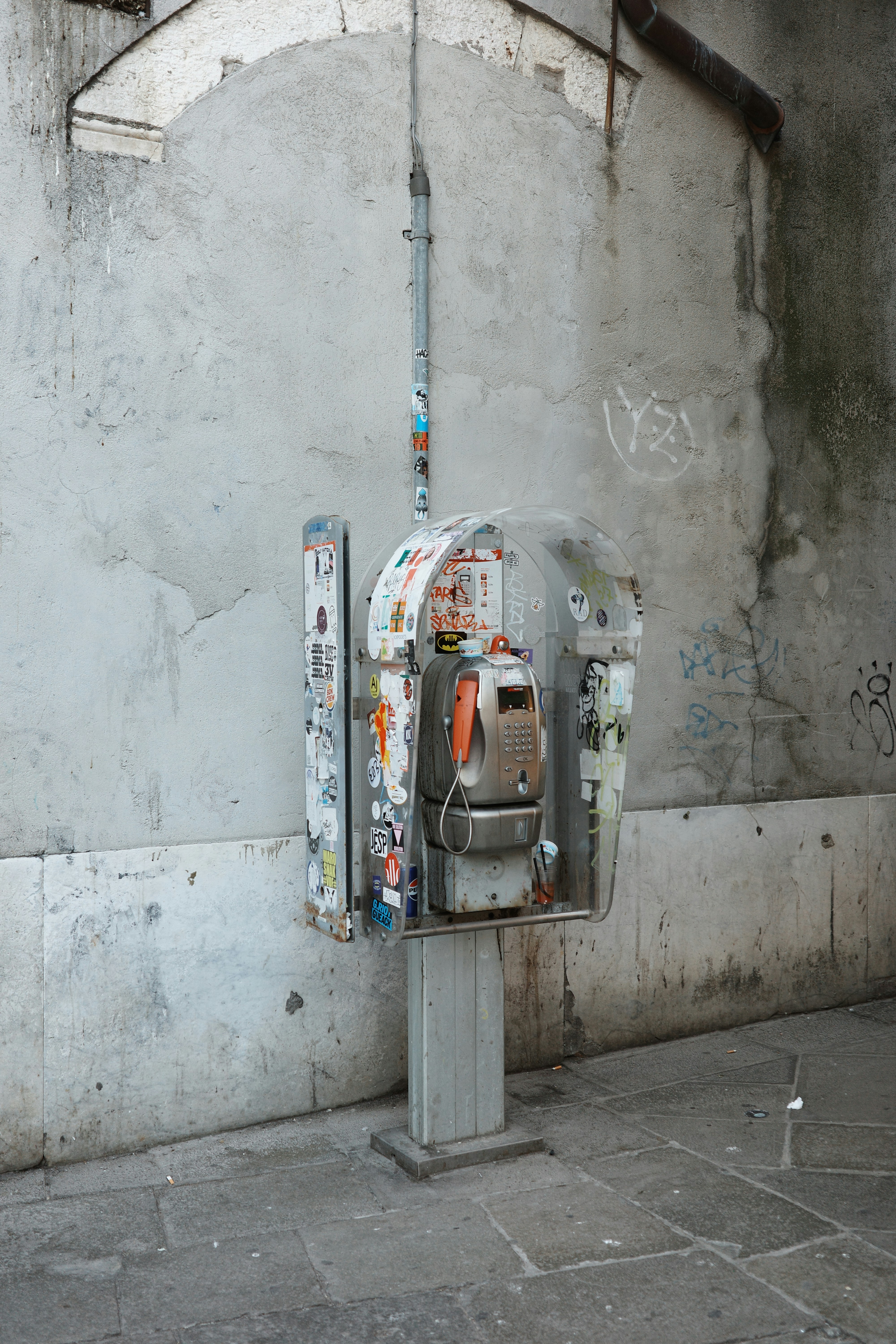 An old, weathered payphone stands against a wall.