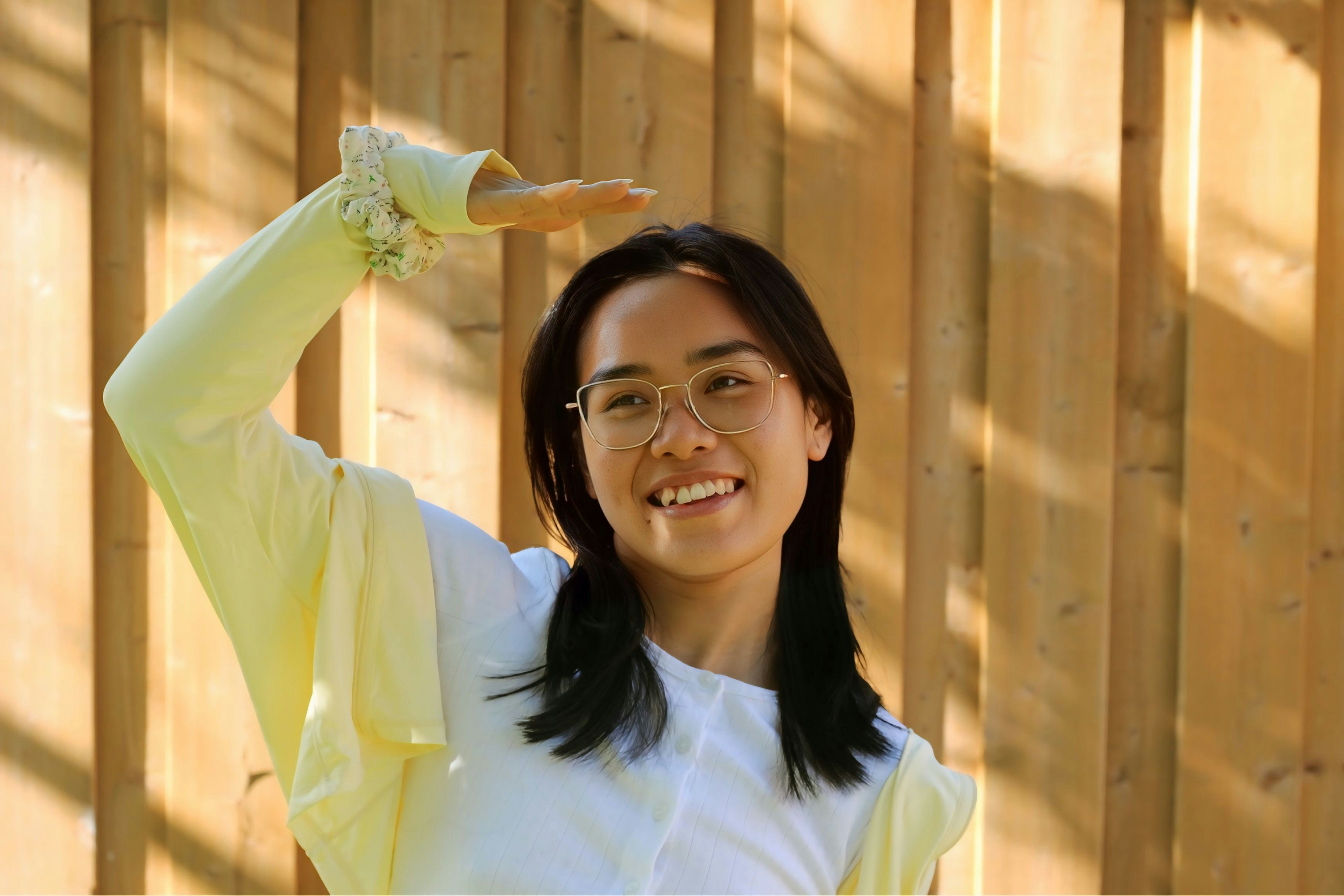 Smiling woman blocks the sun with her hand.