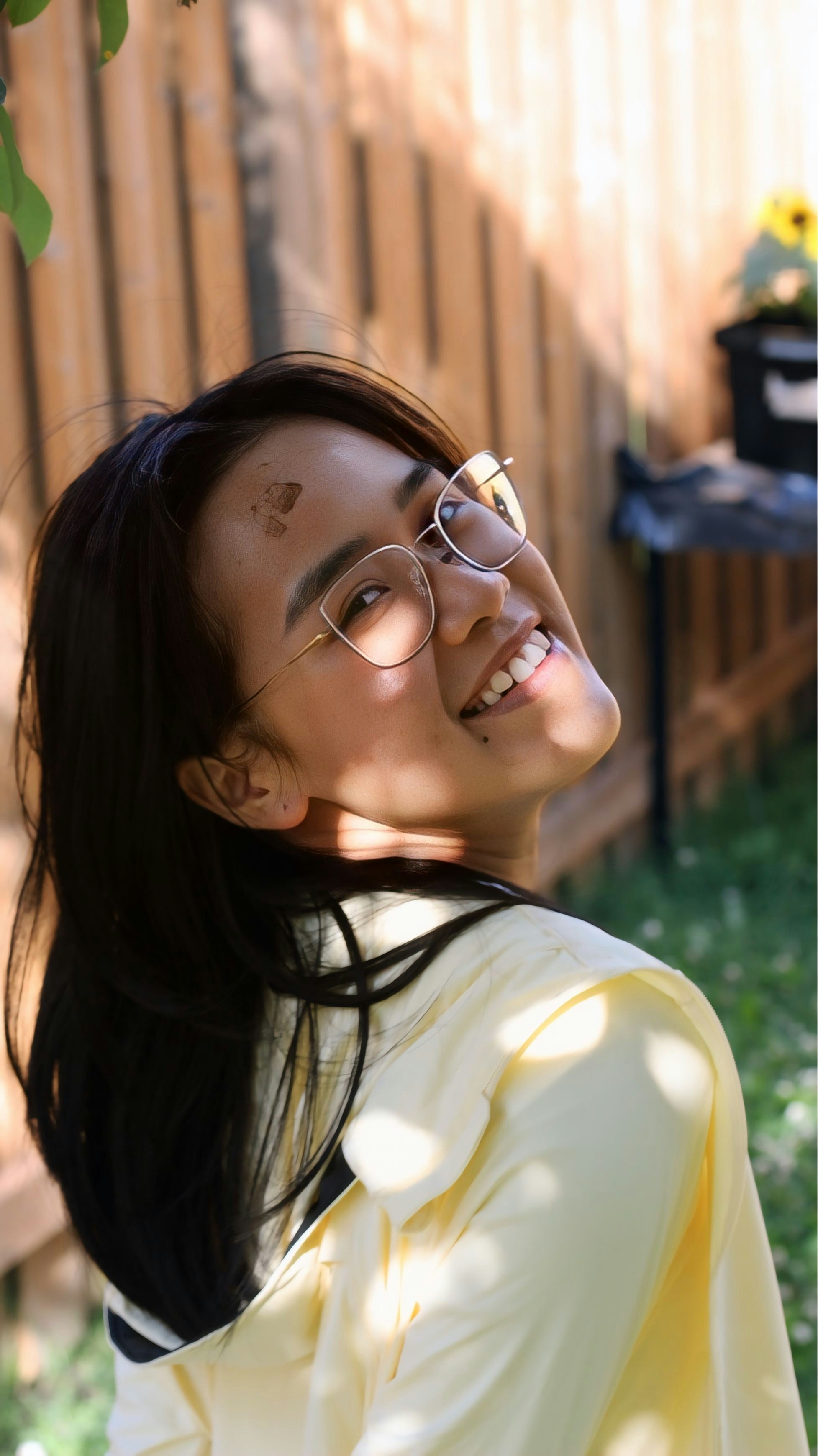 A smiling woman in glasses looks back.