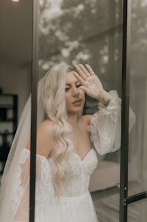 Bride in gown poses by a glass door.
