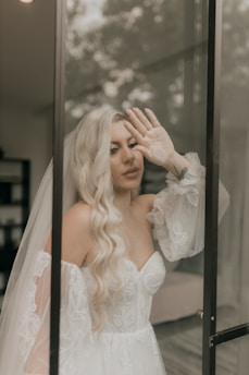 Bride in gown poses by a glass door.
