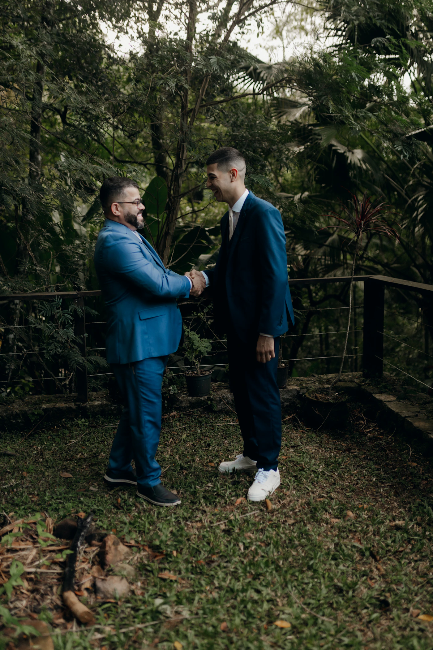 Couple in ceremony attire on a Colombian Pacific beach during their elopement photography session with the rainforest-covered coastline visible in the background