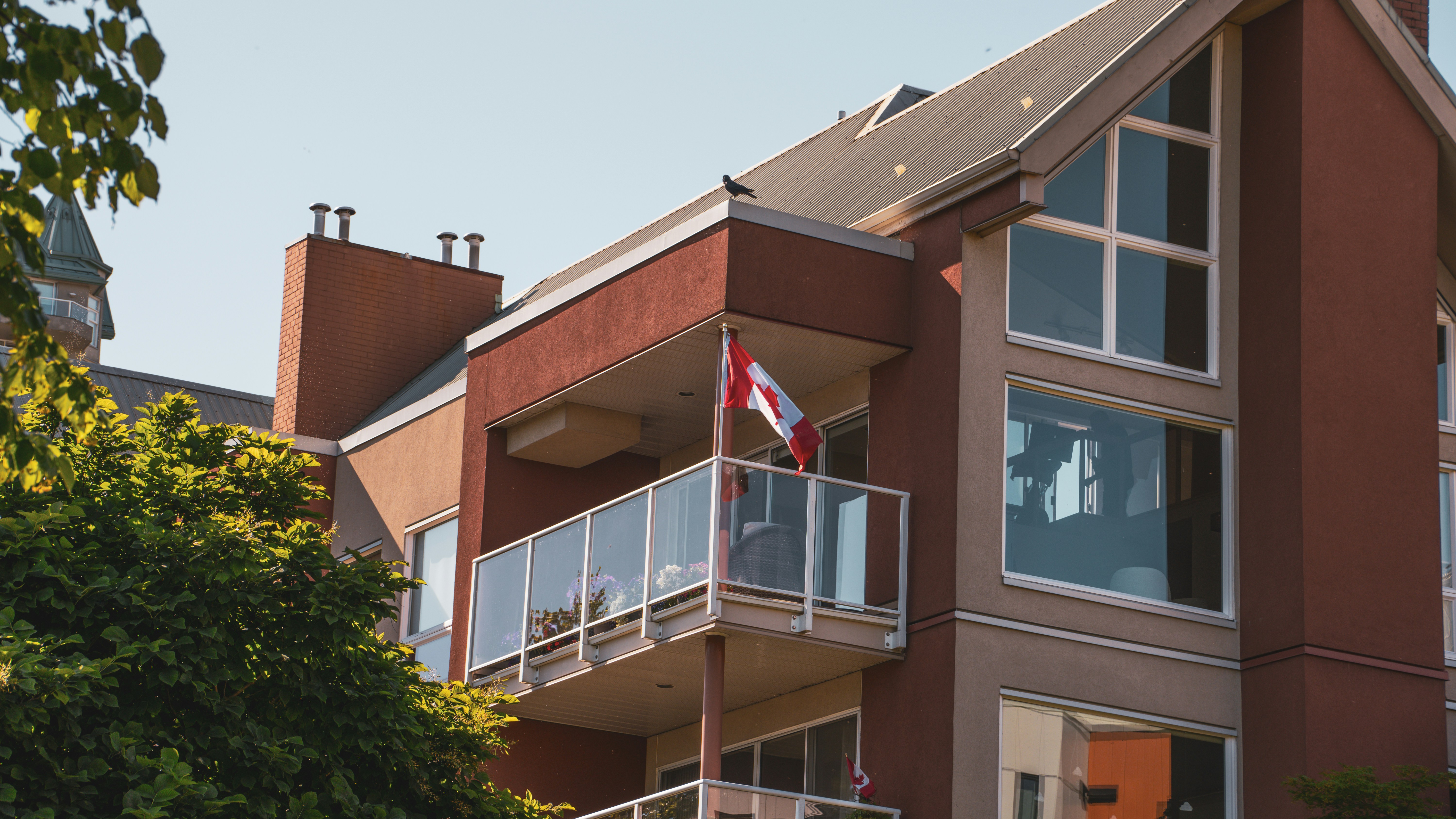 A canadian flag waves from a building balcony.