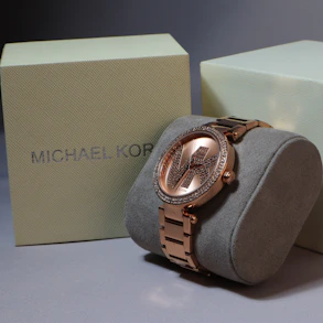 A michael kors watch sits next to its box.