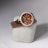 A stylish rose gold watch rests on a display.