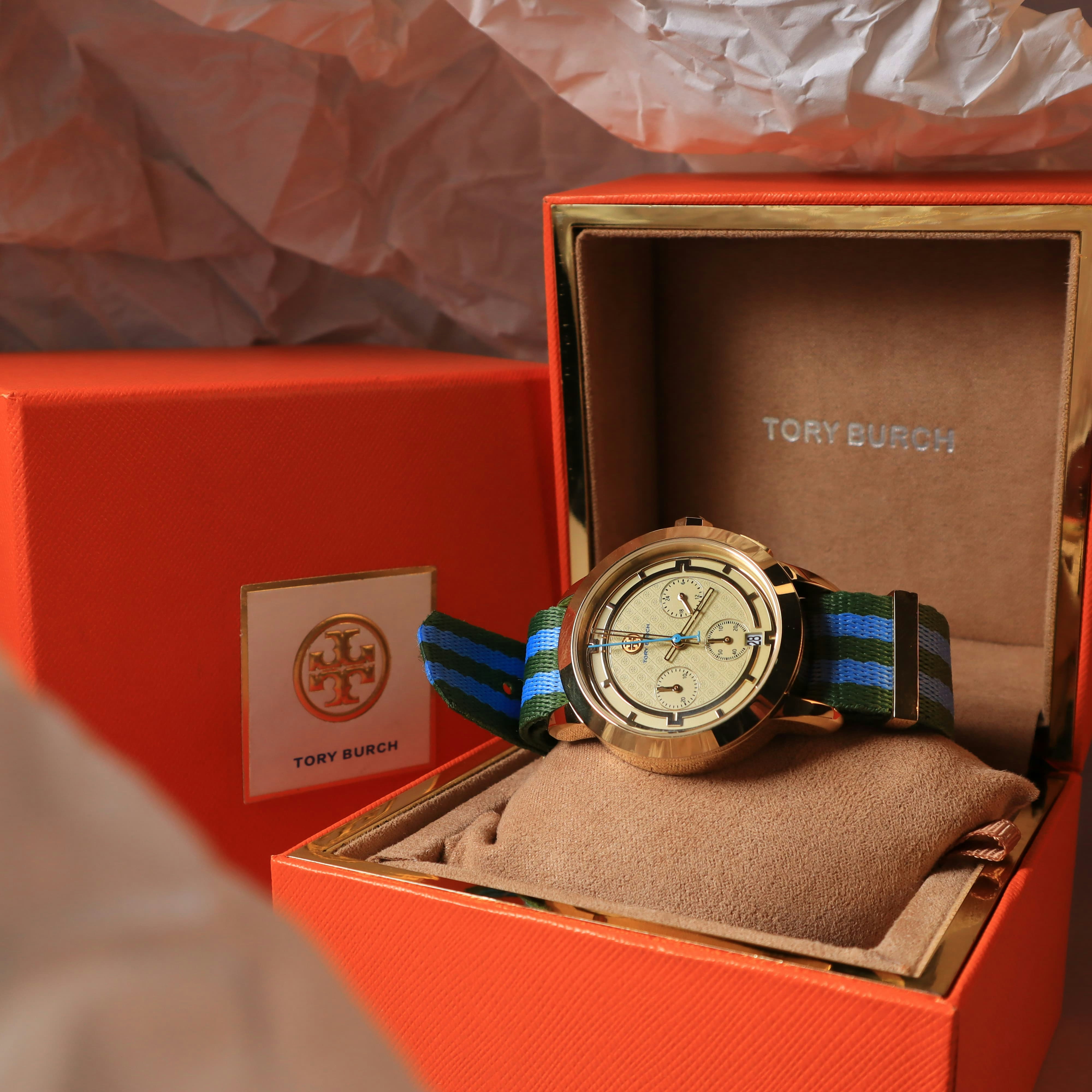 A tory burch watch sits inside its gift box.