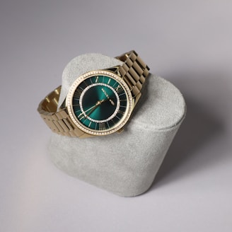 A gold watch displays its emerald green face.