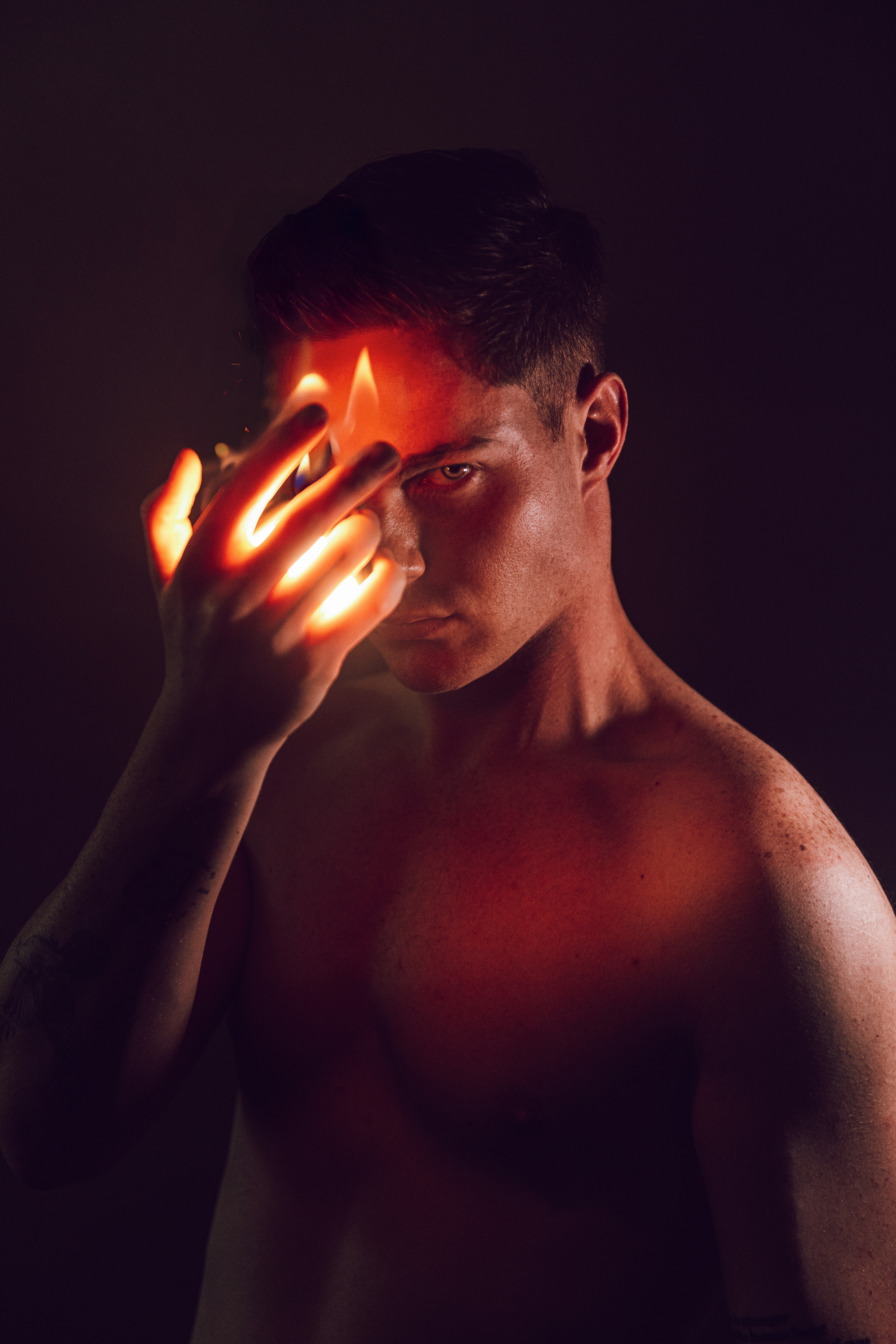 Der Mensch hält eine glühende Flamme vor sein Gesicht.