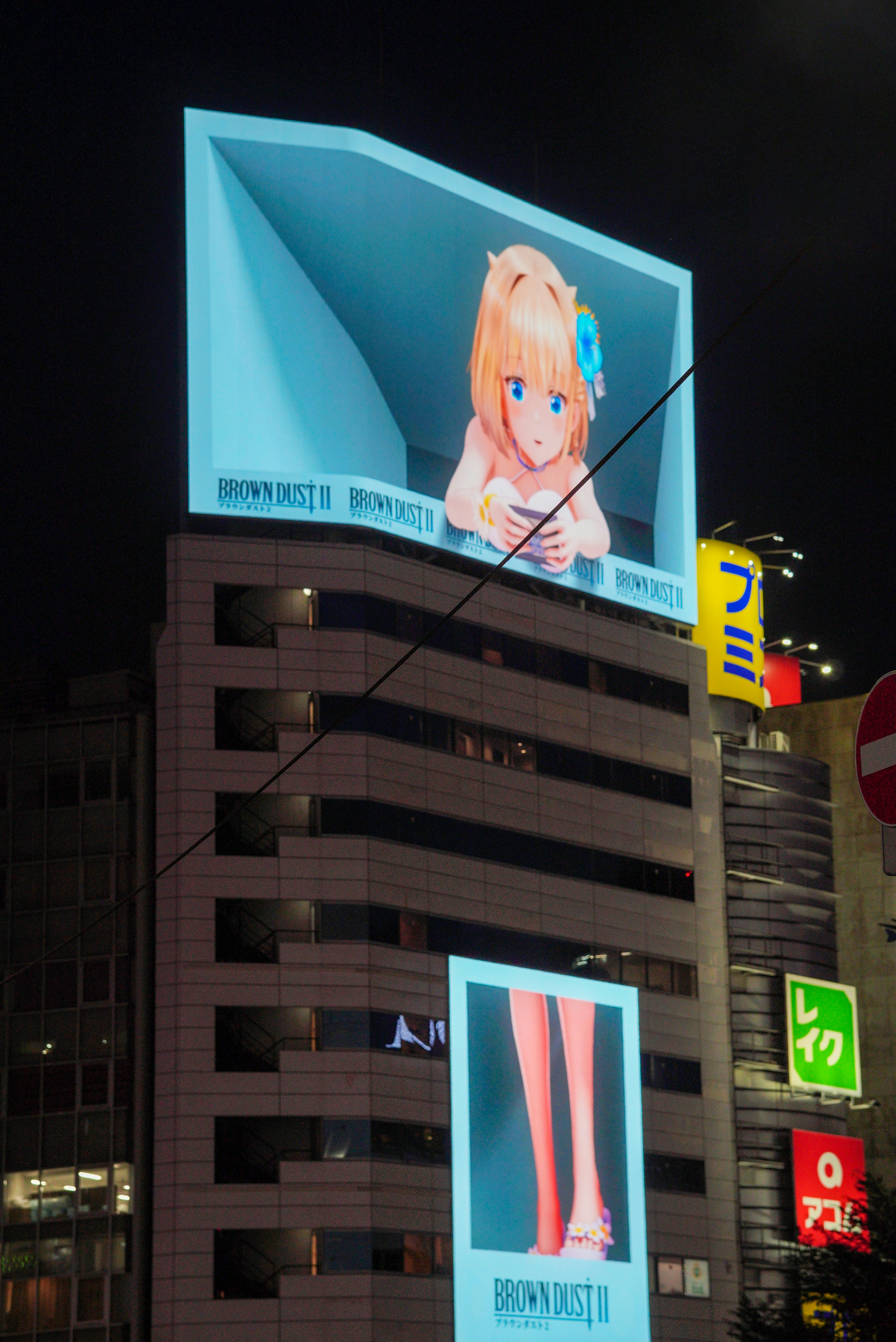 Anime character advertisement lit up on a building.
