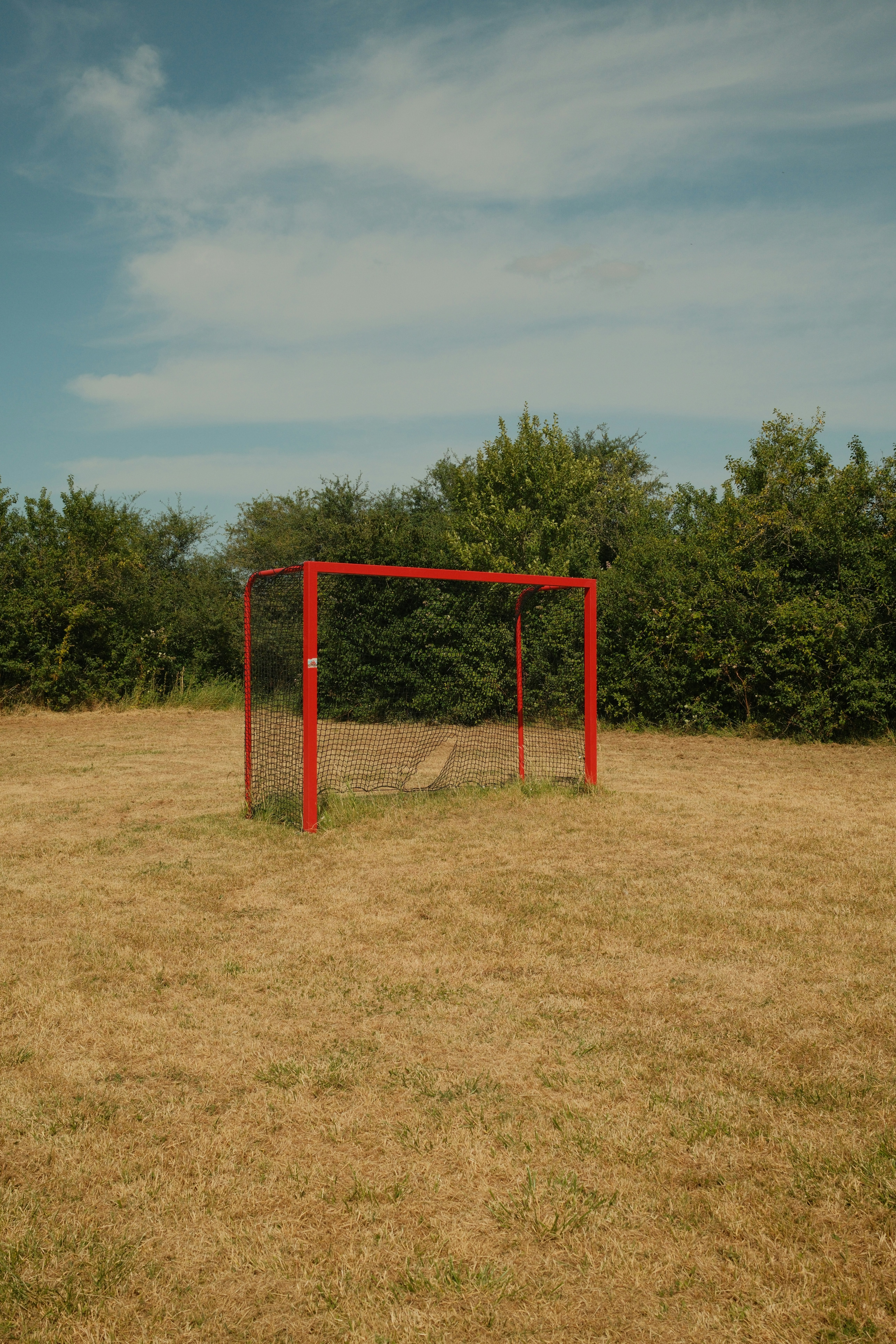 A red goal sits on a dry, brown field.