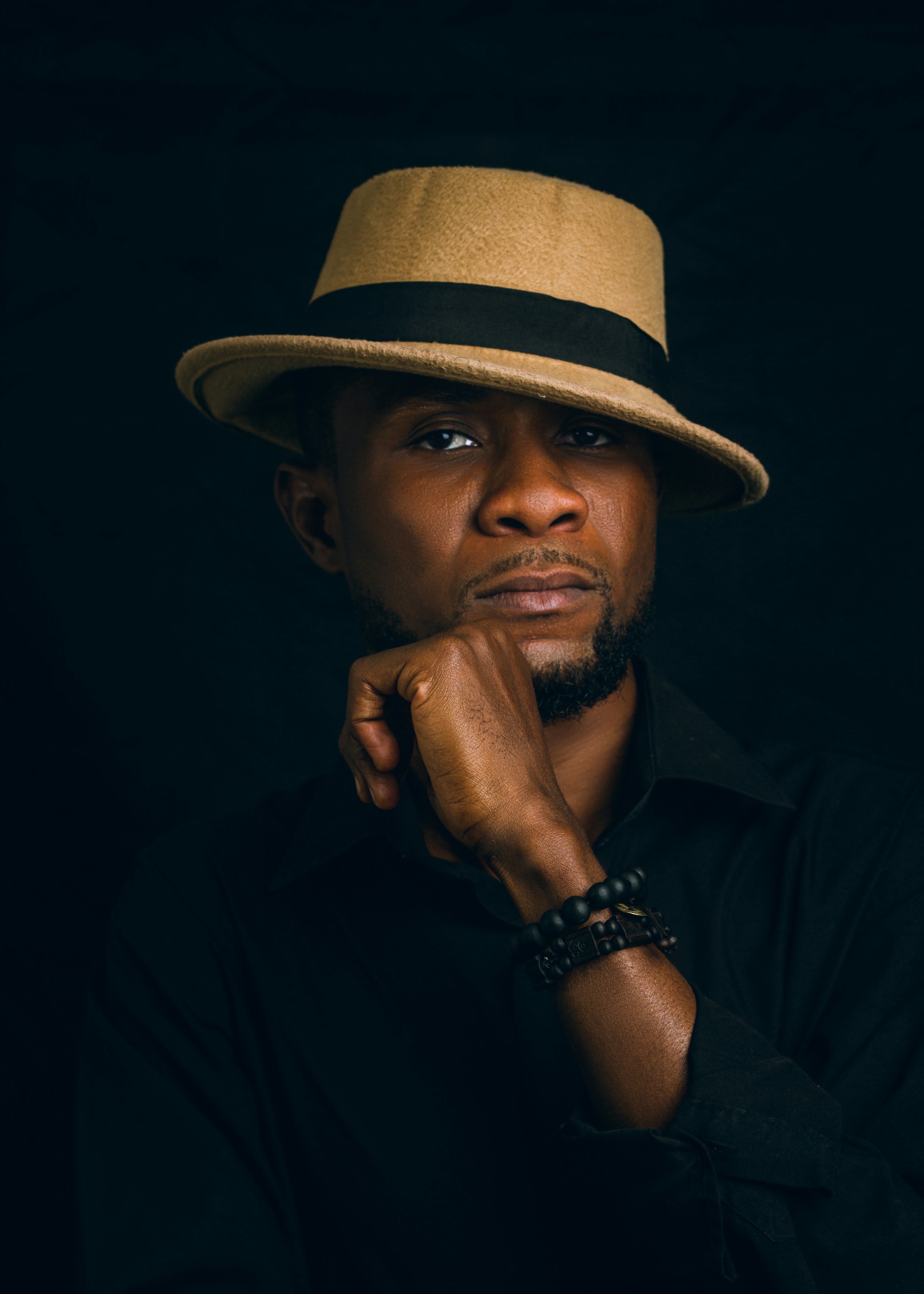 A man poses thoughtfully in a fedora.