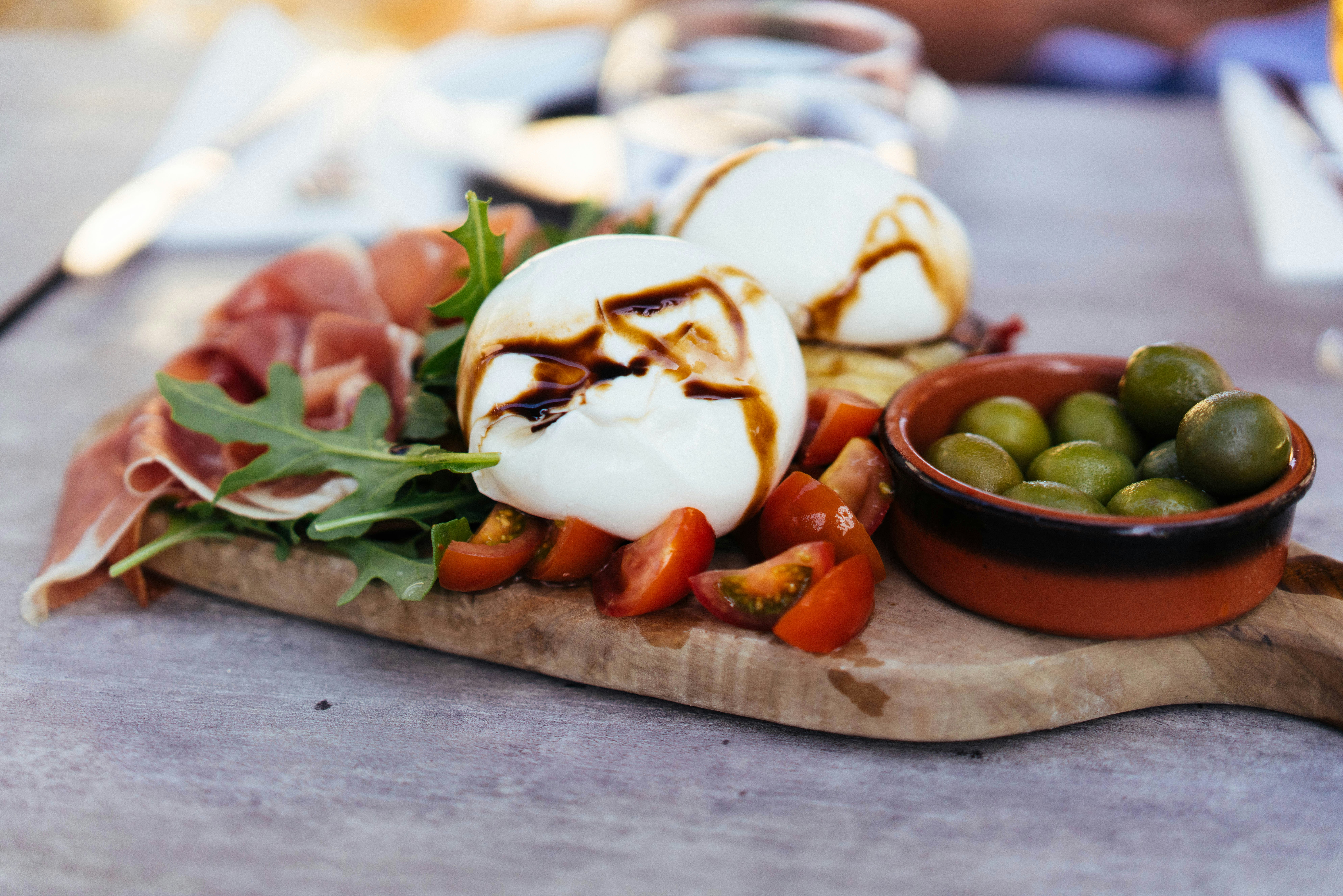 Burrata, tomatoes and olives on a board