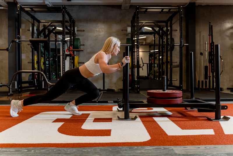 Woman is pushing a sled in a gym.