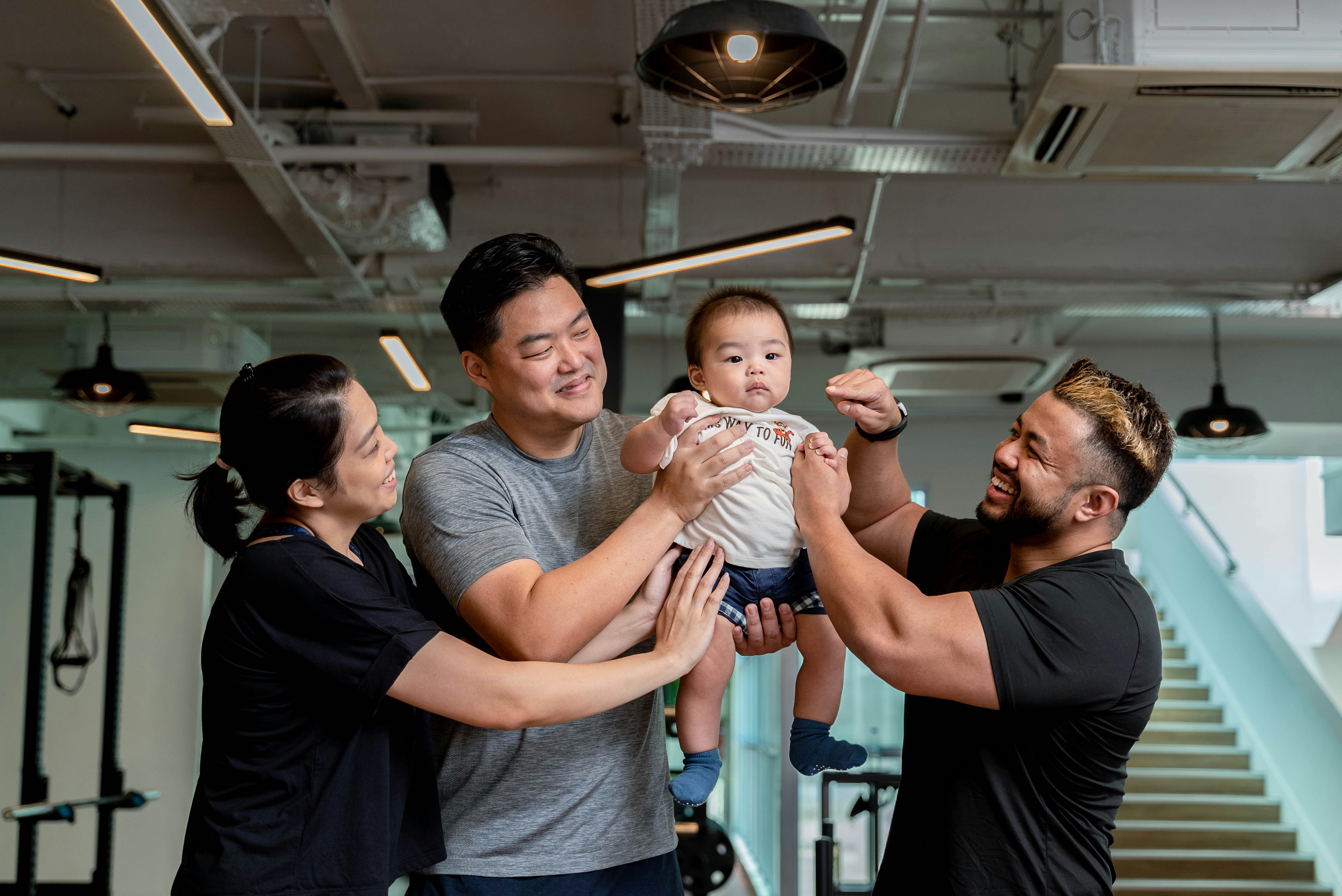Family and trainer celebrate baby in the gym.