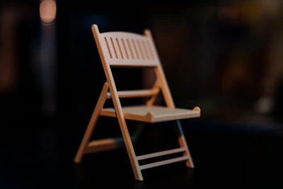 A miniature wooden folding chair stands.