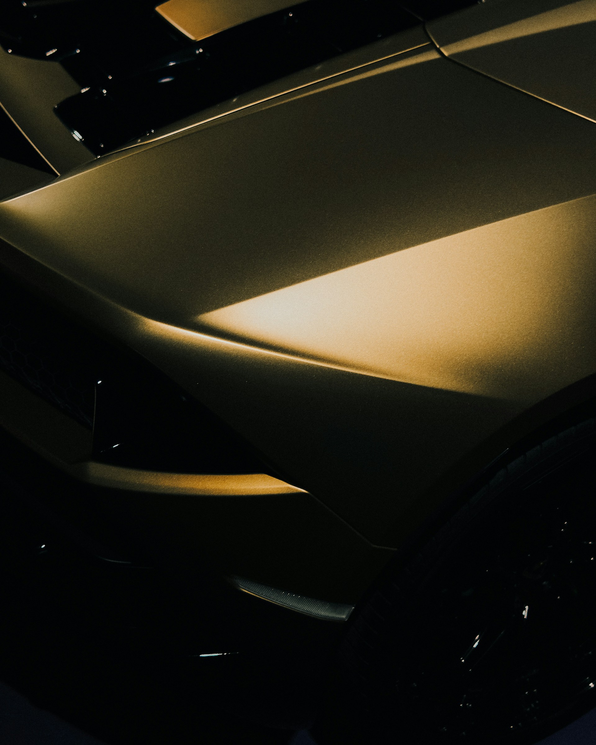 A dark car is bathed in golden light.