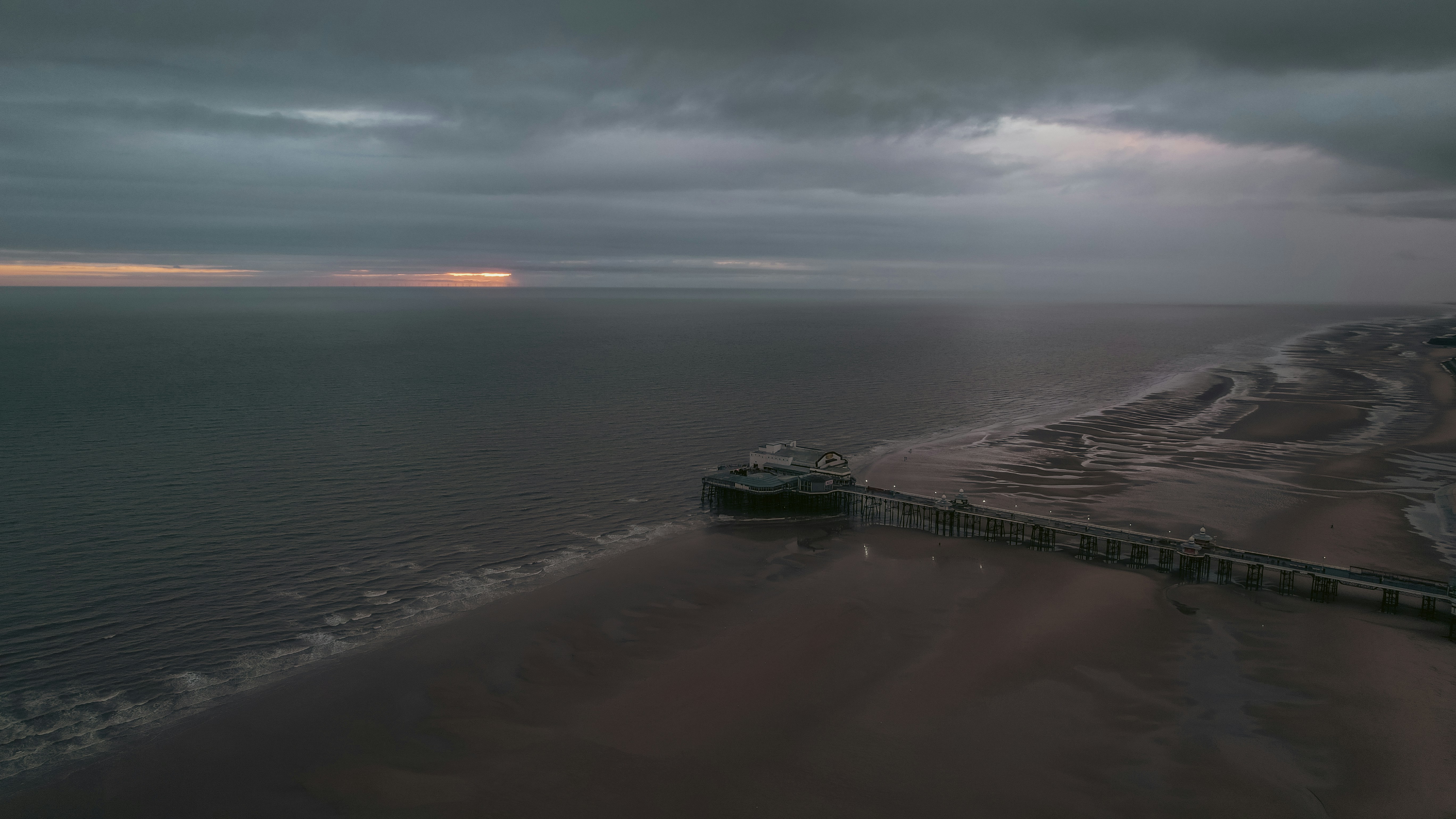 Gloomy beach with a sun setting in the distance.