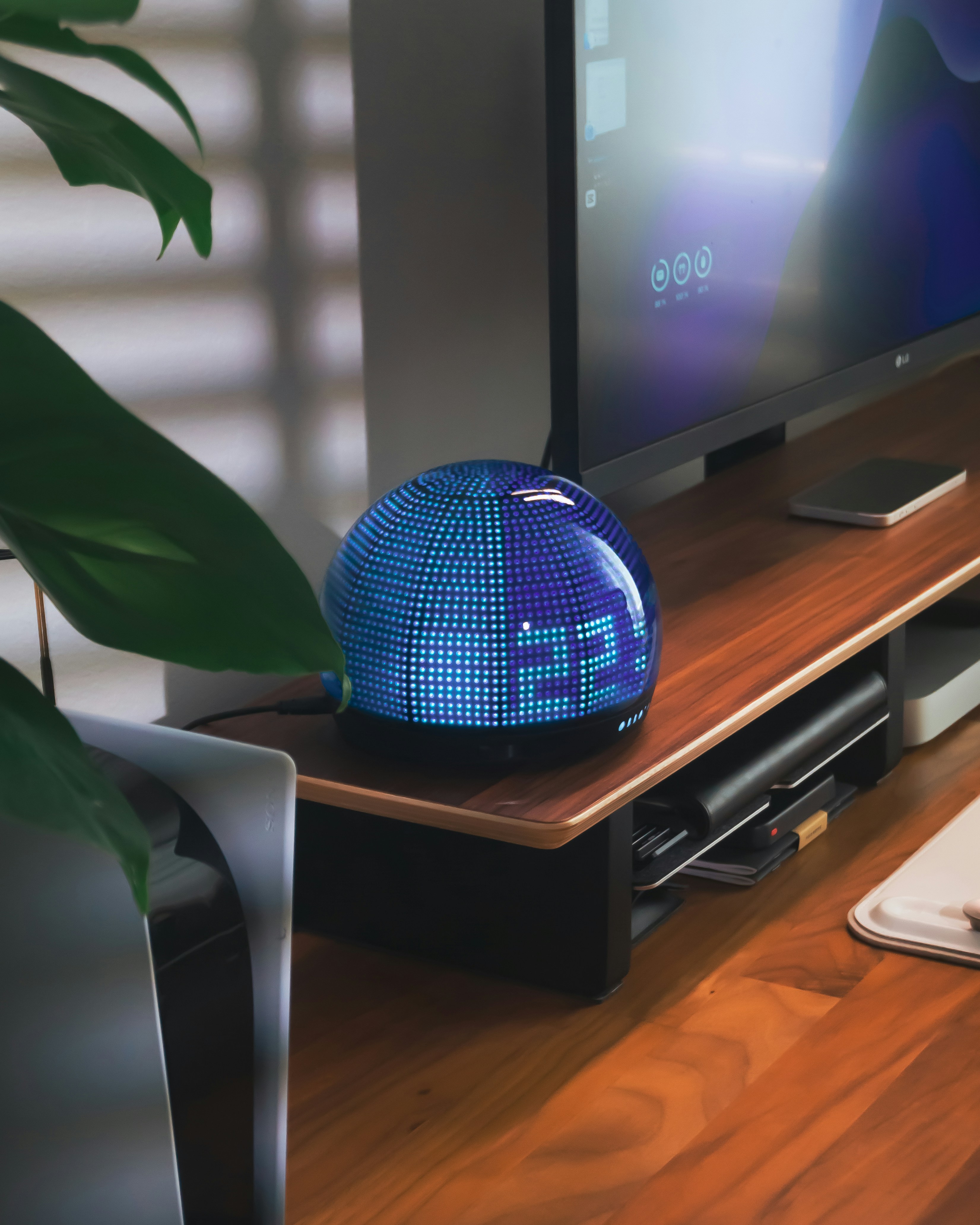 Digital clock sits on a wooden desk.