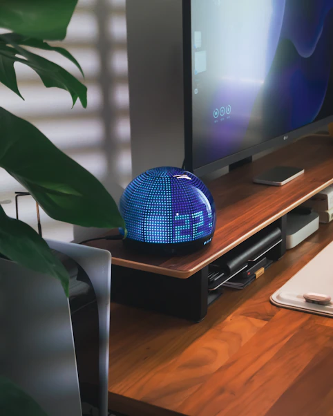 A blue led clock sits on a wooden desk.