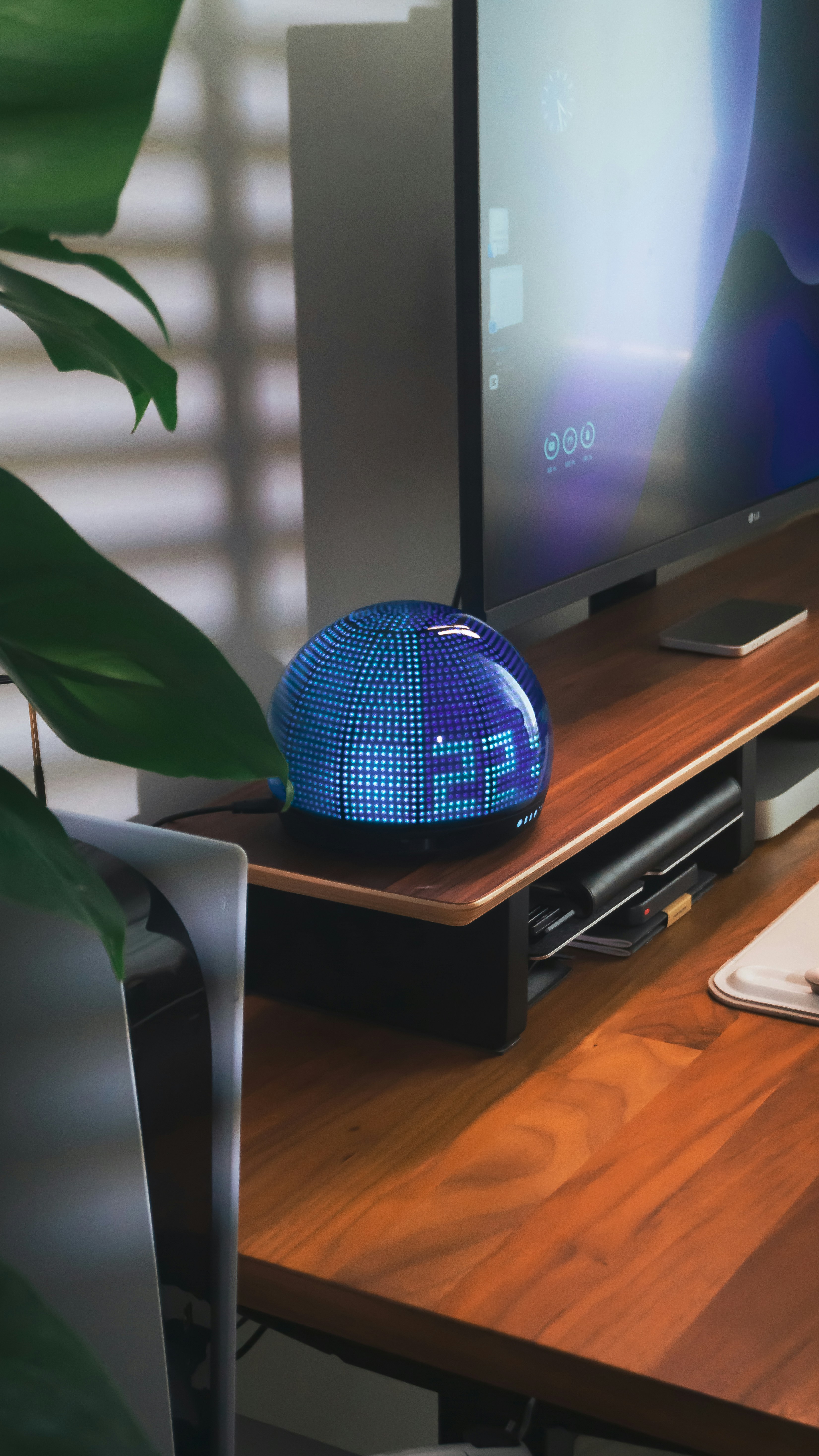 A futuristic digital clock rests on a wooden desk.