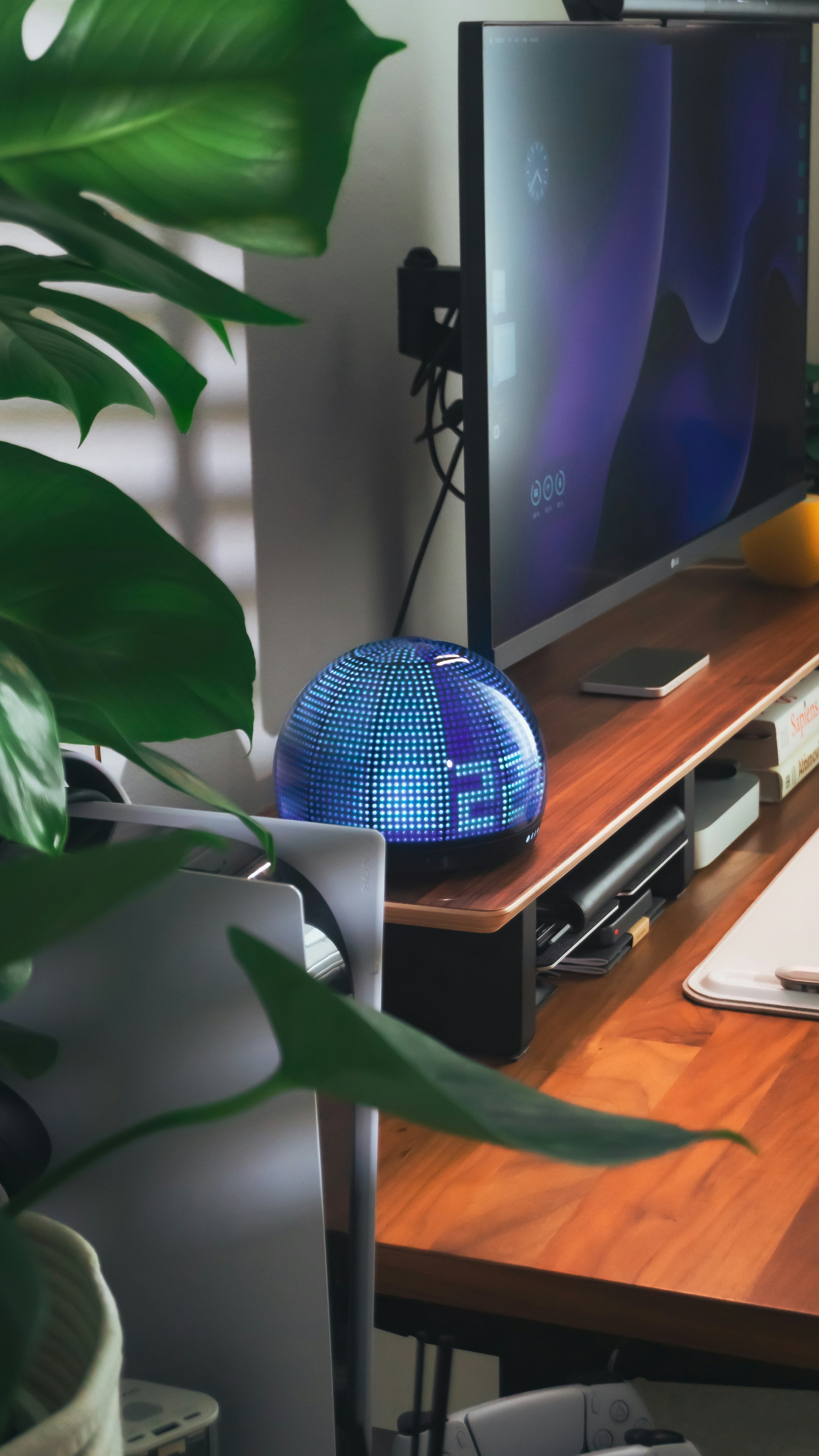 A modern clock sits on a wooden desk.